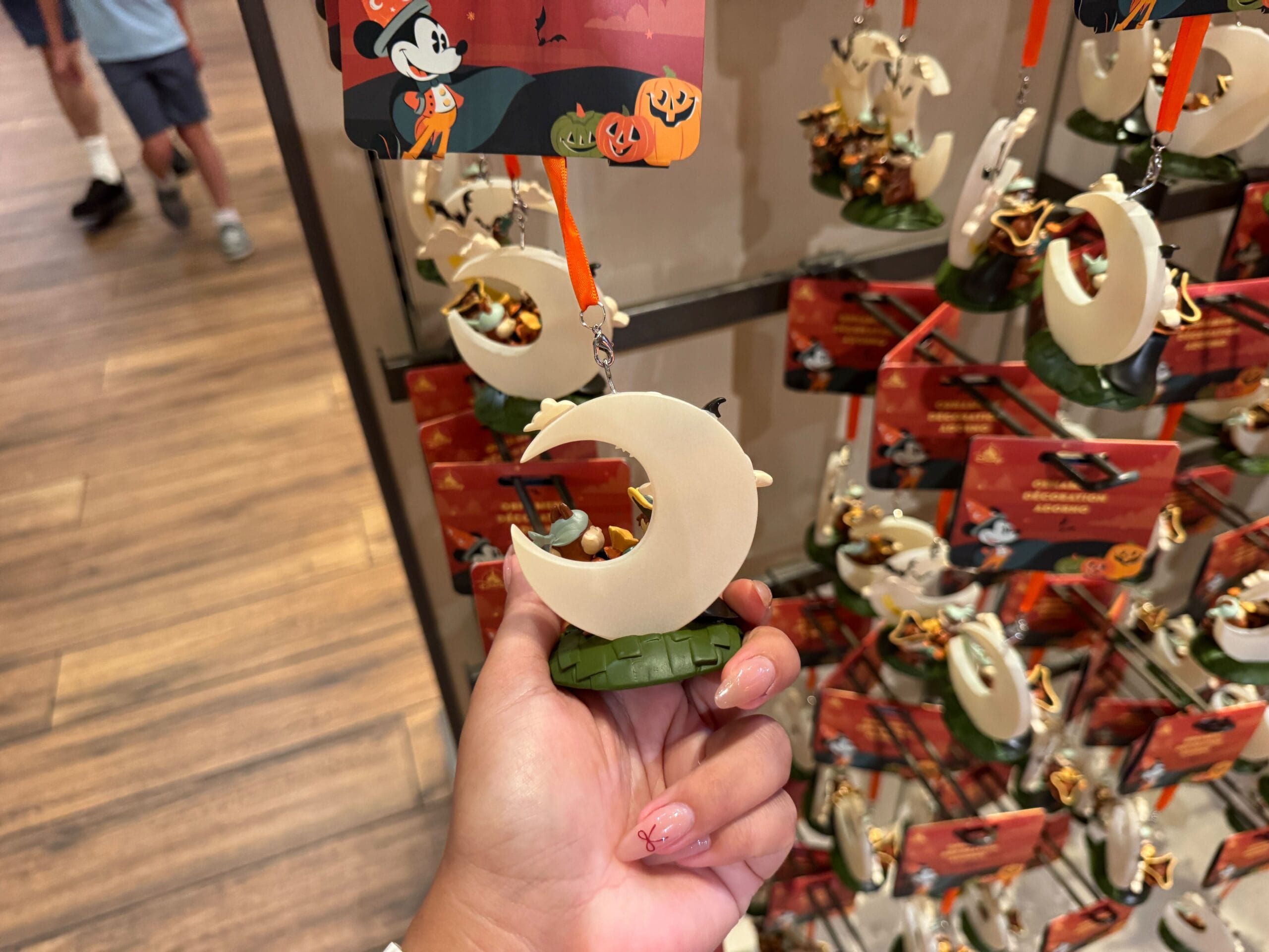 Hand holding a crescent moon Halloween ornament with teeth, part of 2025 Halloween merchandise at Walt Disney World.