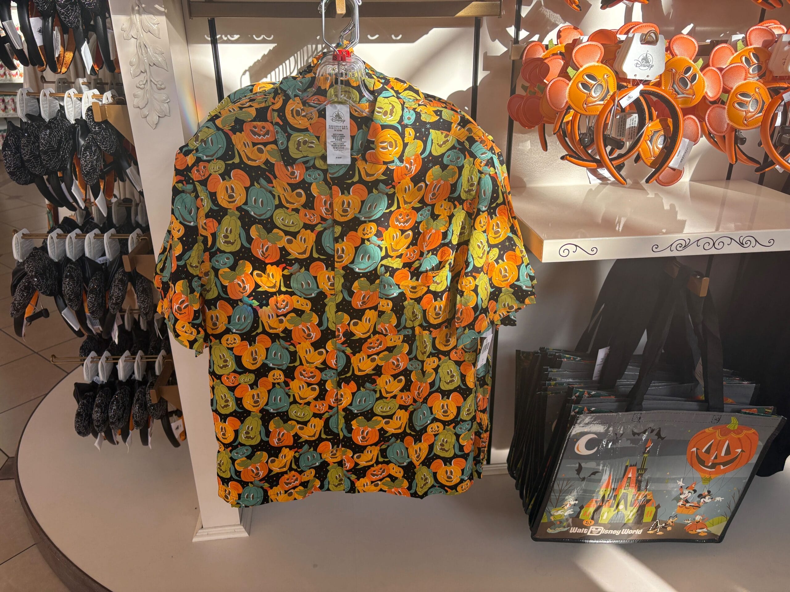 Disney Halloween Merch 2025 - A shirt with colorful Mickey Mouse pumpkins hangs amid Halloween merchandise at Walt Disney World.