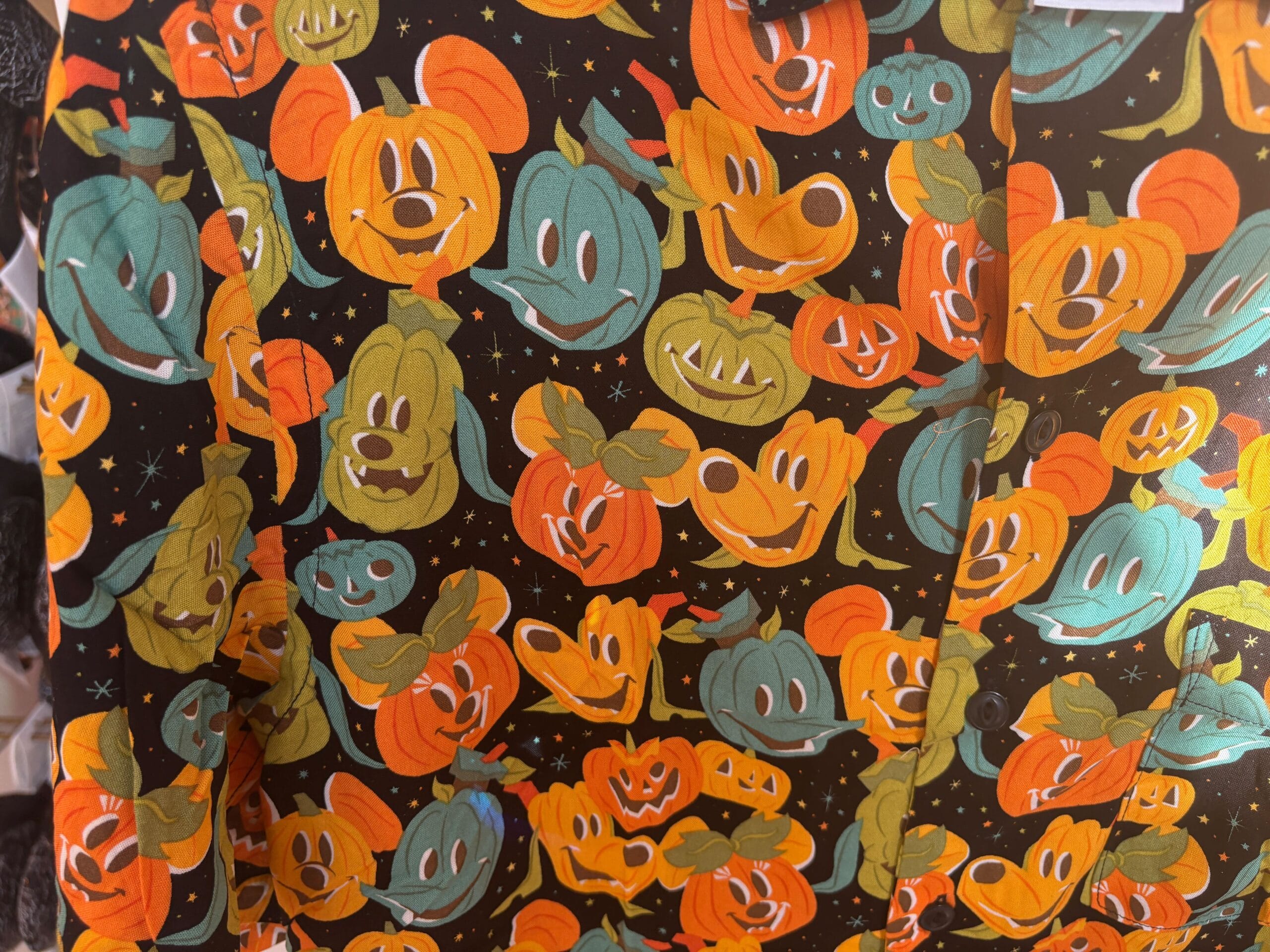 Shirt with colorful pumpkin faces, inspired by Walt Disney World Halloween merchandise, on a starry black background.