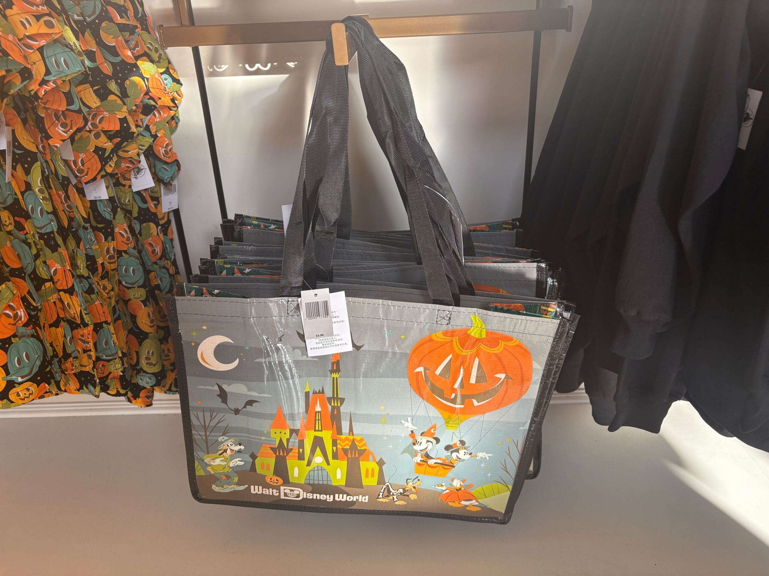 Halloween merchandise at Walt Disney World: tote bags with cartoon characters, pumpkins, and a spooky castle on display.