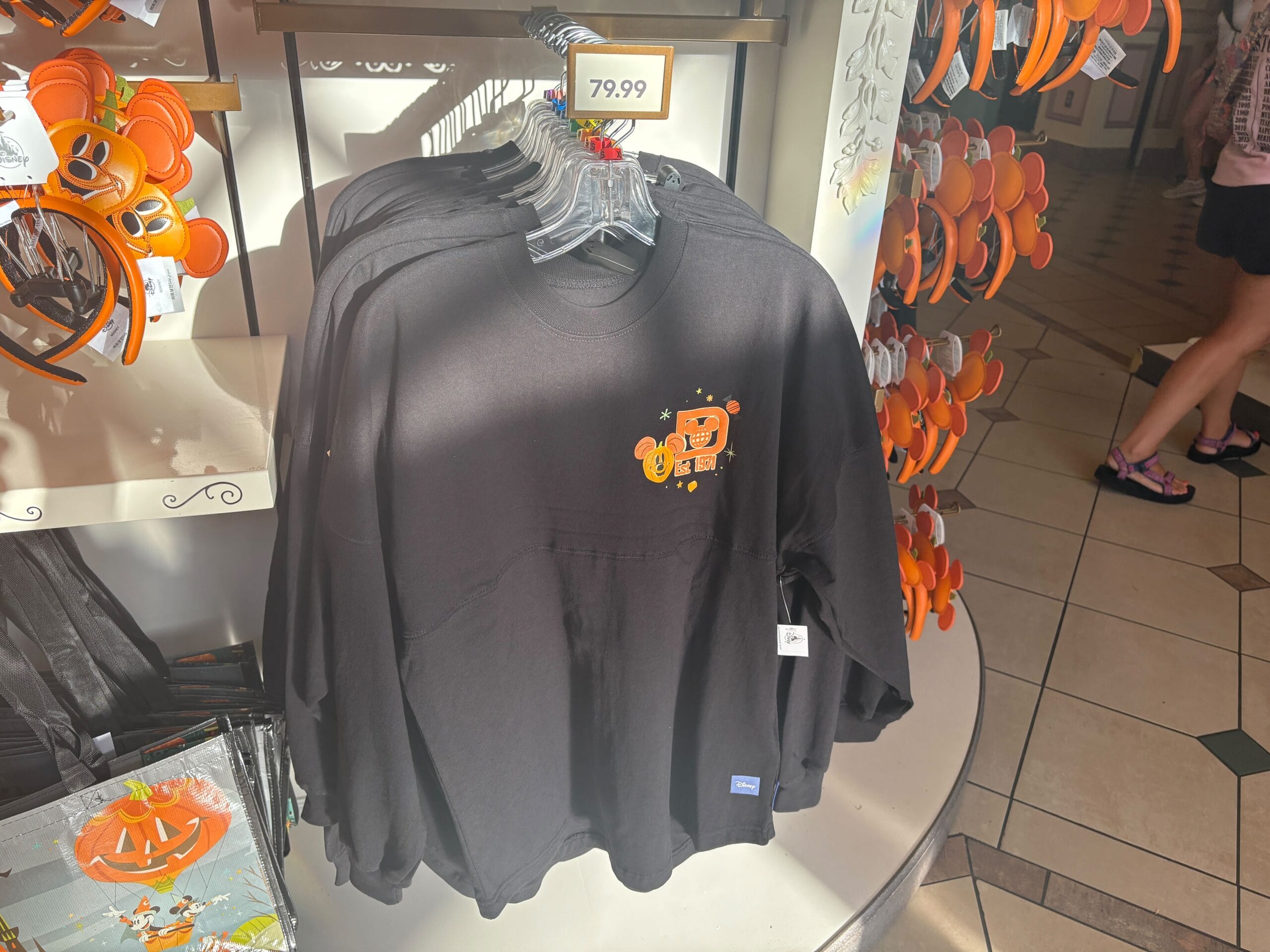Disney Halloween Merch 2025 -Black Walt Disney World Halloween sweatshirt with Mickey pumpkin design on hangers, price tag shows $79.99 above.