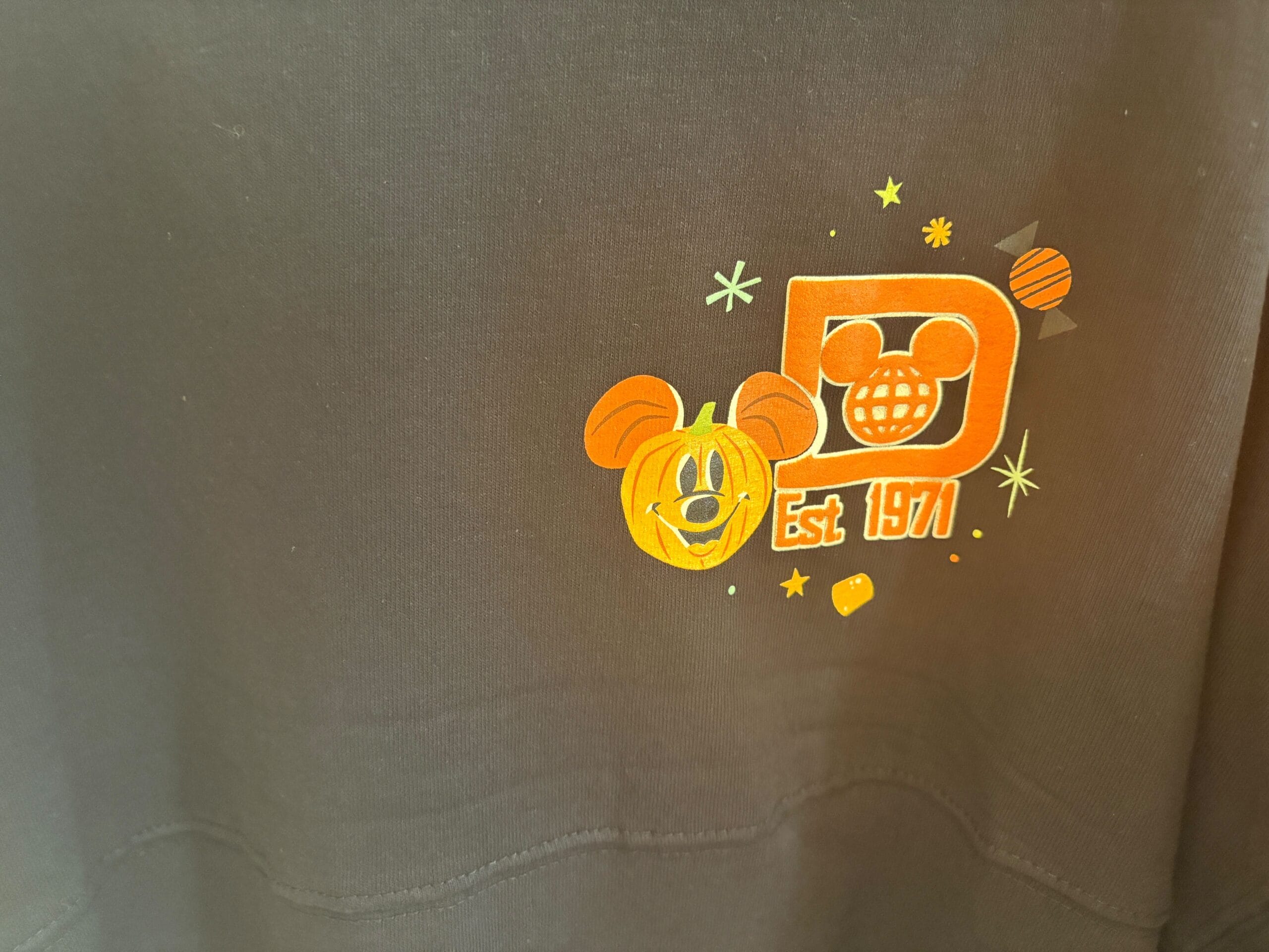 Black fabric with a small orange Mickey Mouse pumpkin, "D," "Est 1971," and Walt Disney World Halloween merchandise elements.