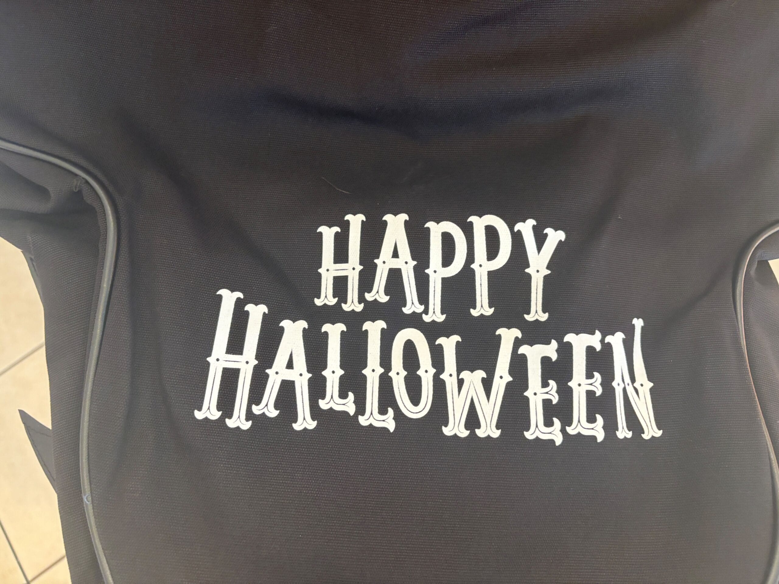 Black fabric featuring "Happy Halloween" in spooky white letters—perfect for Halloween merchandise at Walt Disney World.