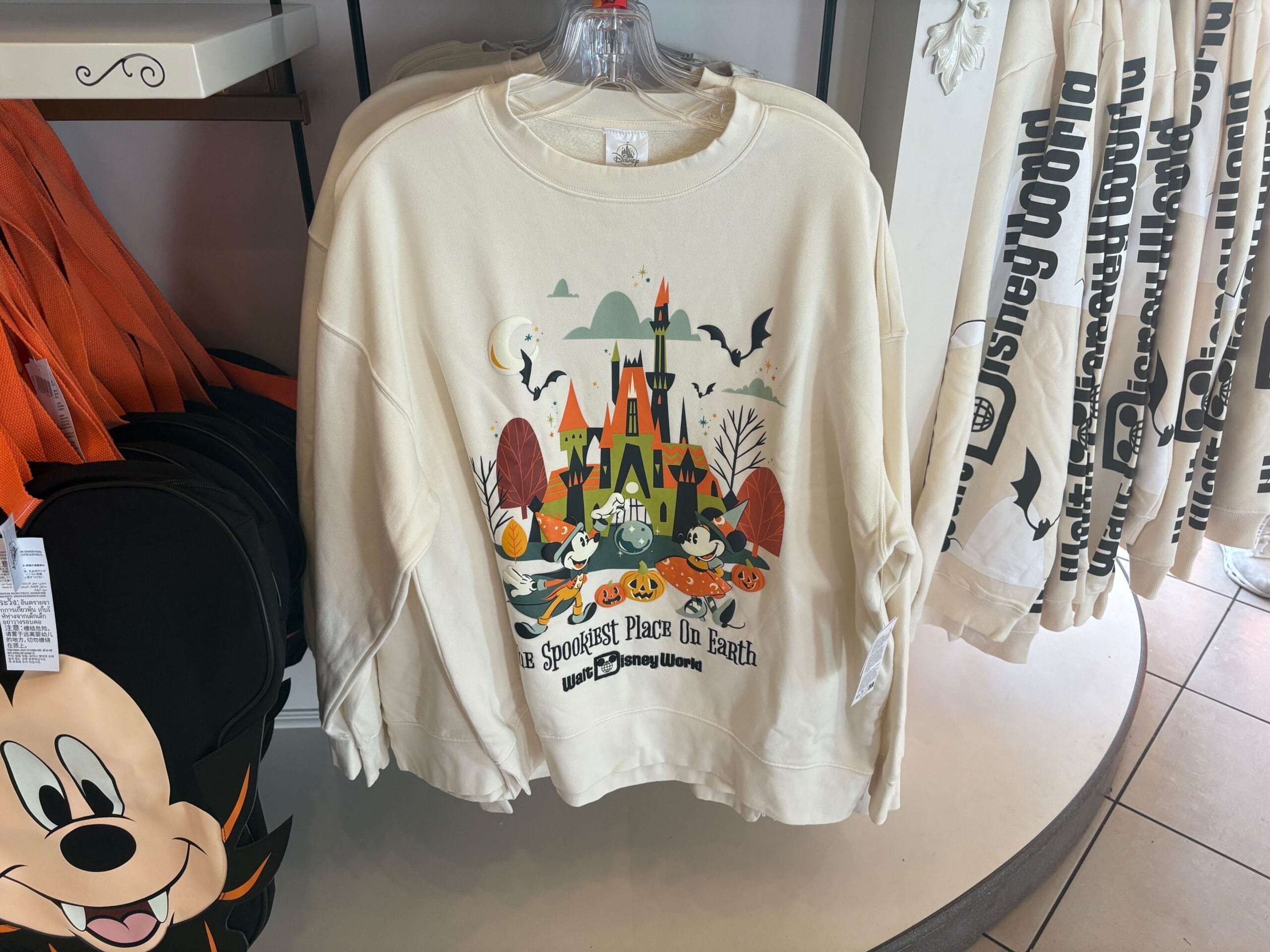 Disney Halloween Merch 2025 - Cream Walt Disney World sweatshirt with Halloween castle, pumpkins, ghosts, and bats—festive Halloween merchandise in-store.