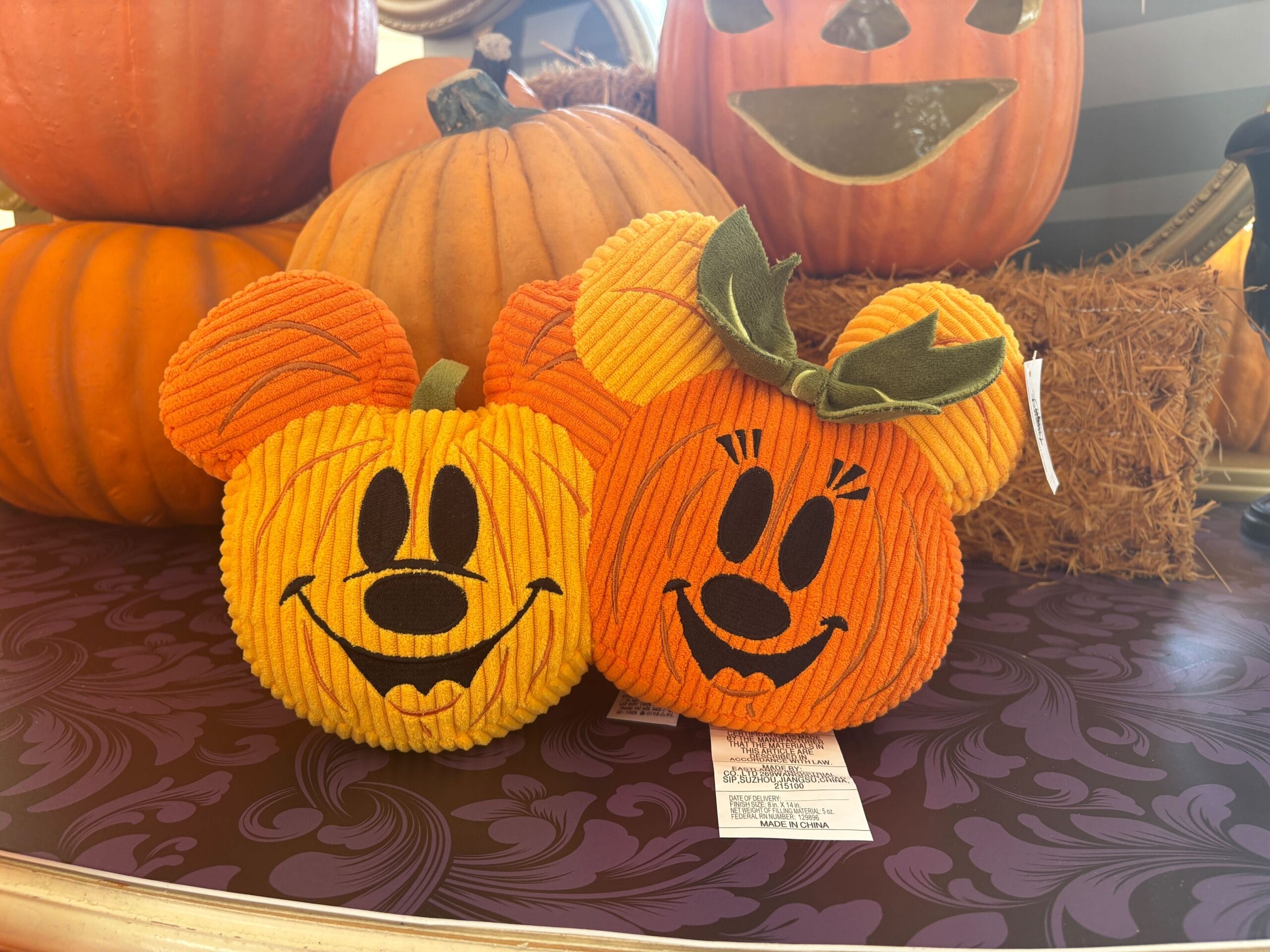 Two plush pumpkin decorations shaped like Mickey and Minnie Mouse add Halloween magic to Walt Disney World tables.
