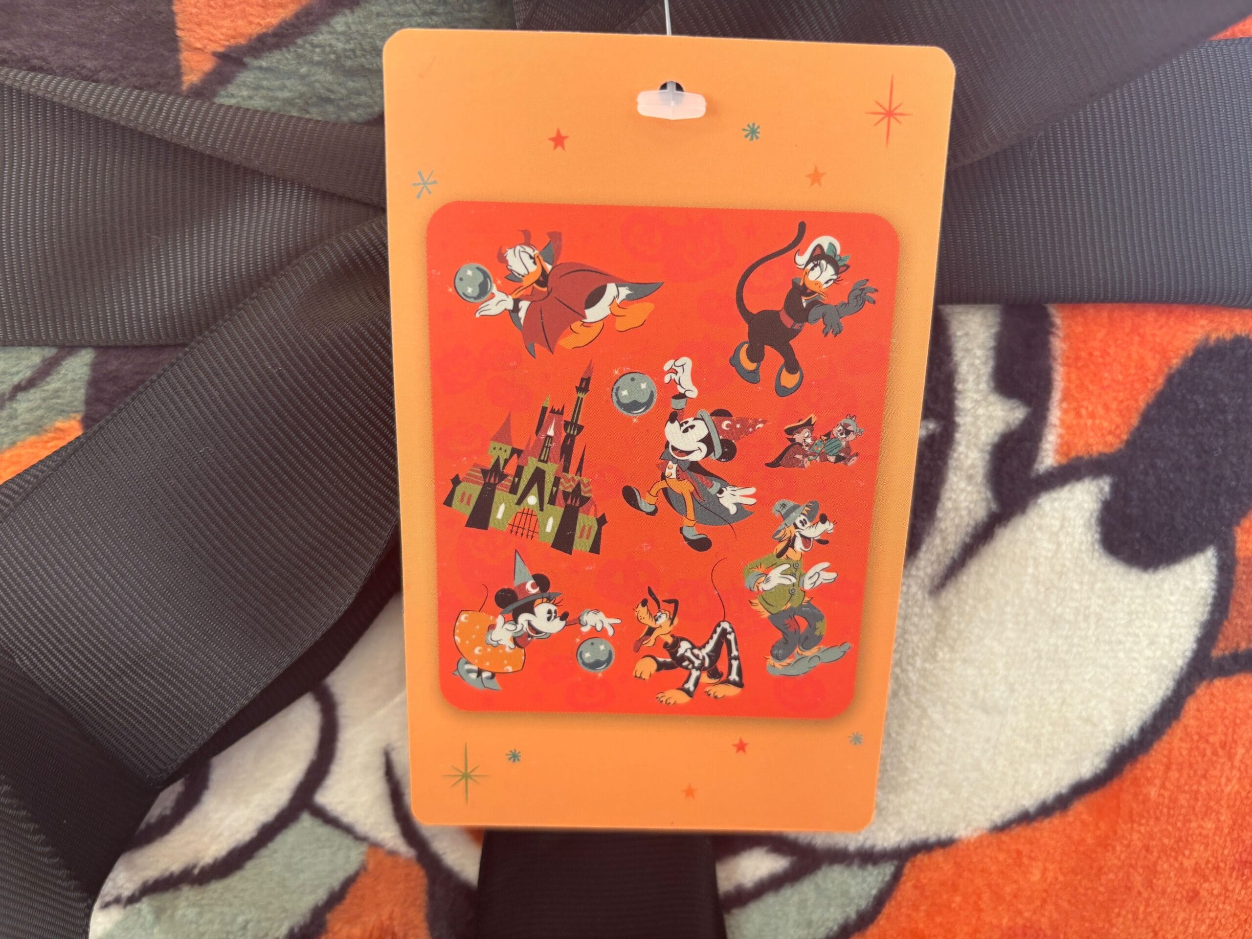 A tag featuring Walt Disney World characters on an orange and black patterned Halloween merchandise background.