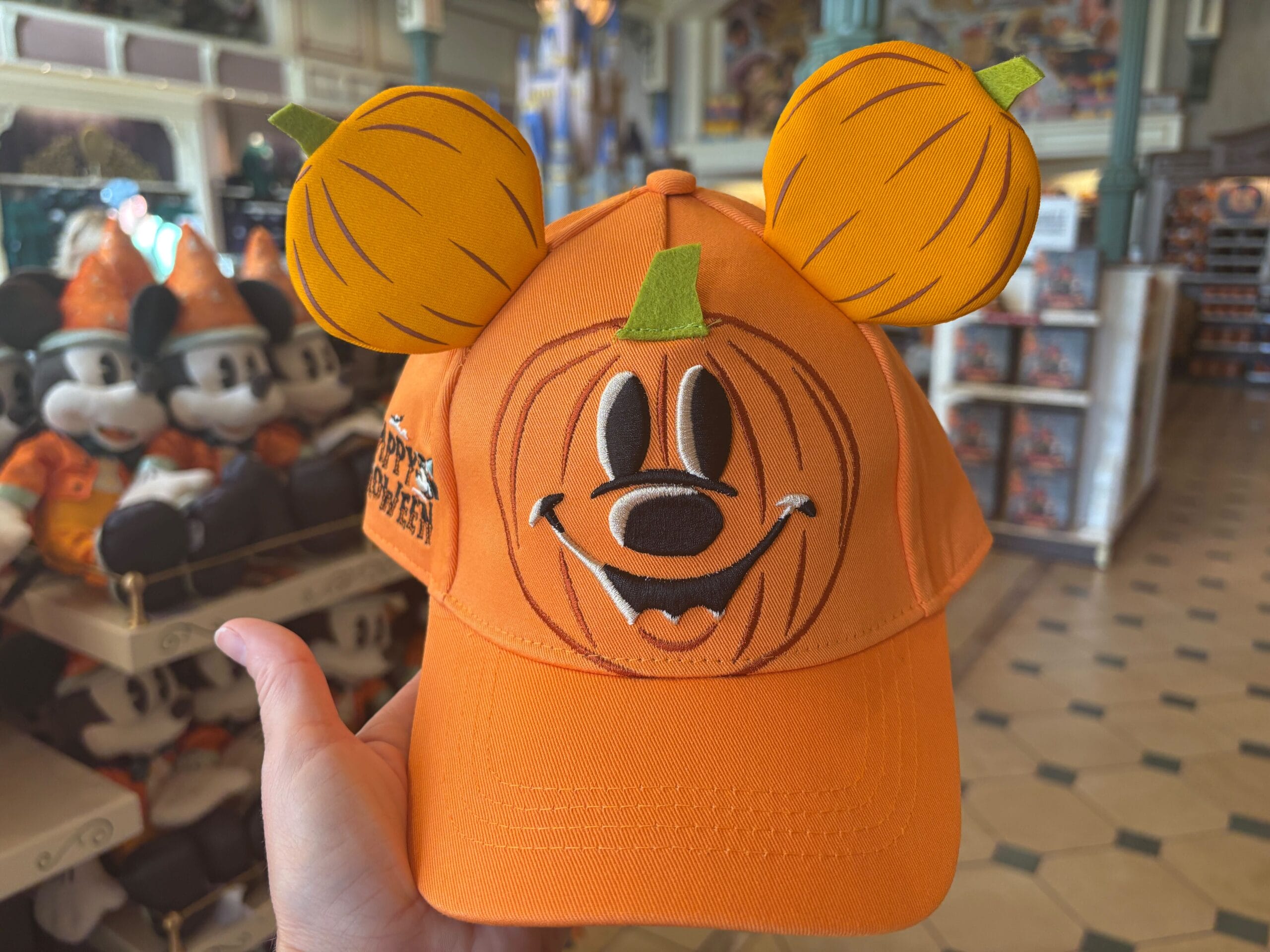 Orange Halloween merchandise hat with a pumpkin Mickey face, spotted at Walt Disney World among plush toys.