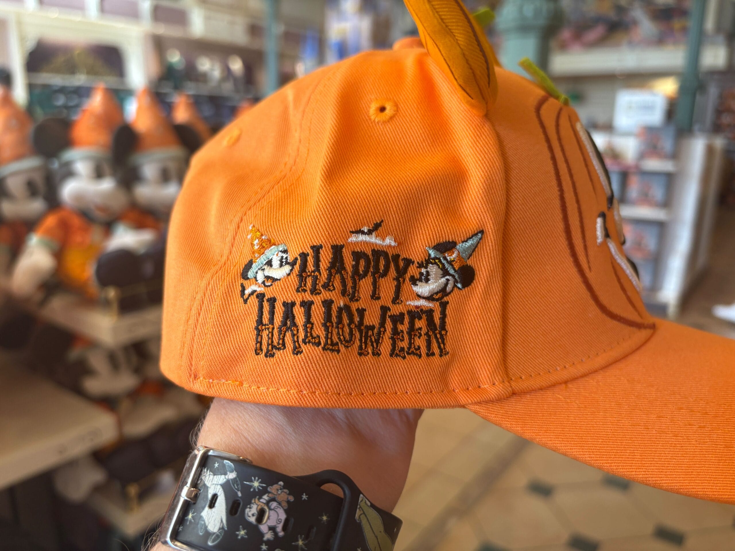 Orange hat with "Happy Halloween" and cartoon characters, spotted among Halloween merchandise in a decorated store.