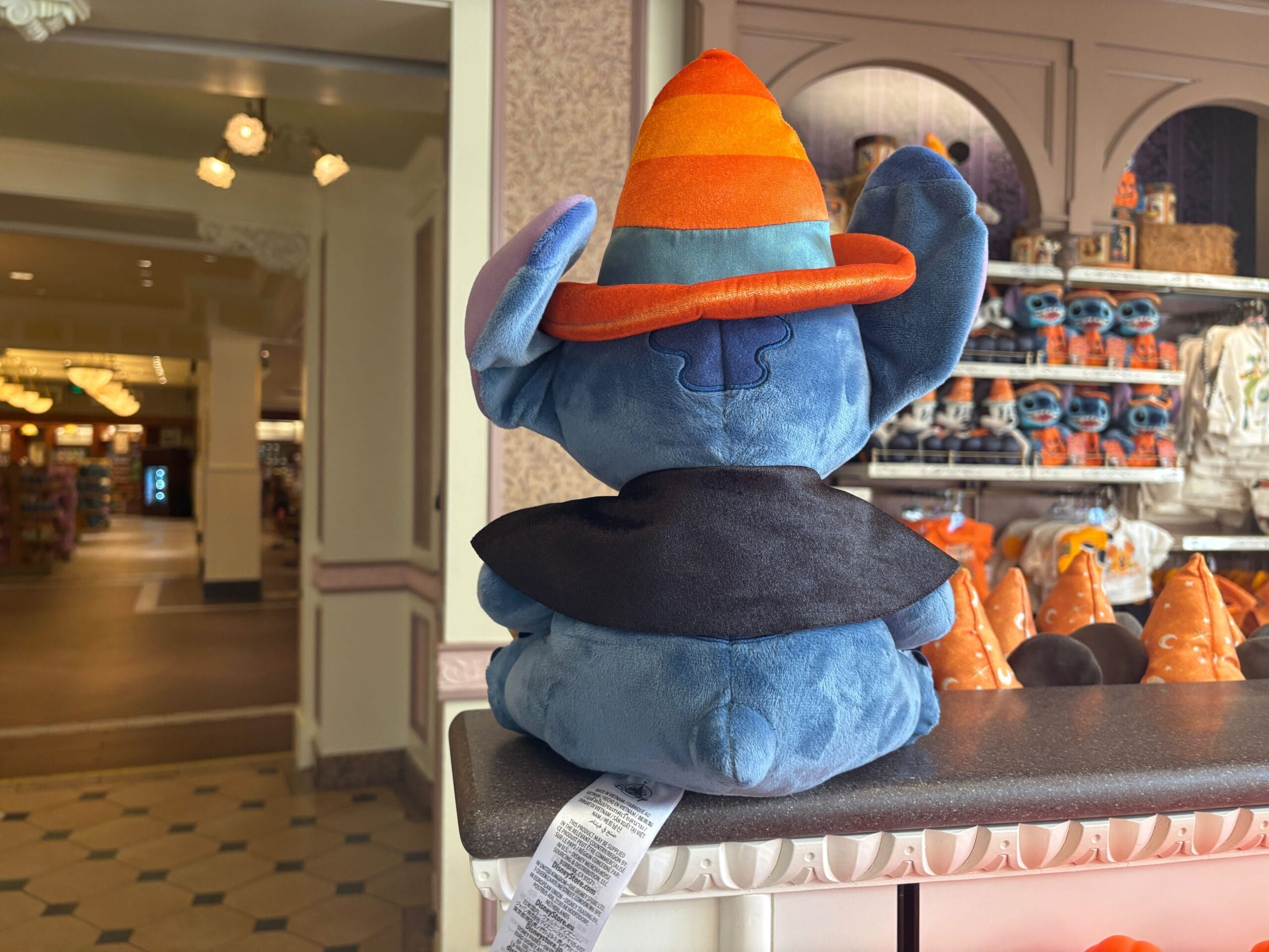 A plush Stitch toy in a wizard costume sits on a store counter, part of Walt Disney World Halloween merchandise.