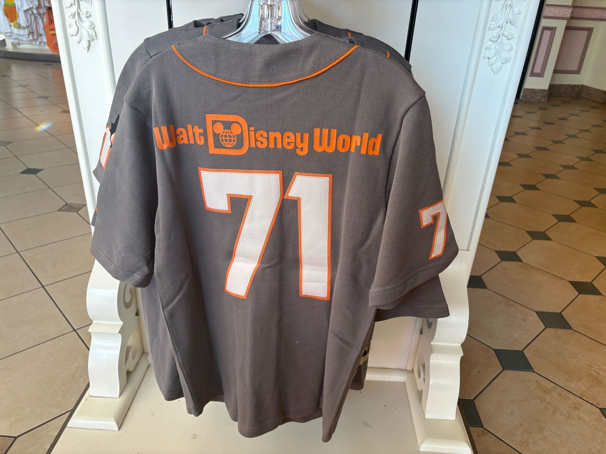 Gray shirt featuring "Walt Disney World" and 71 in orange and white on the back, perfect for Halloween merchandise displays.