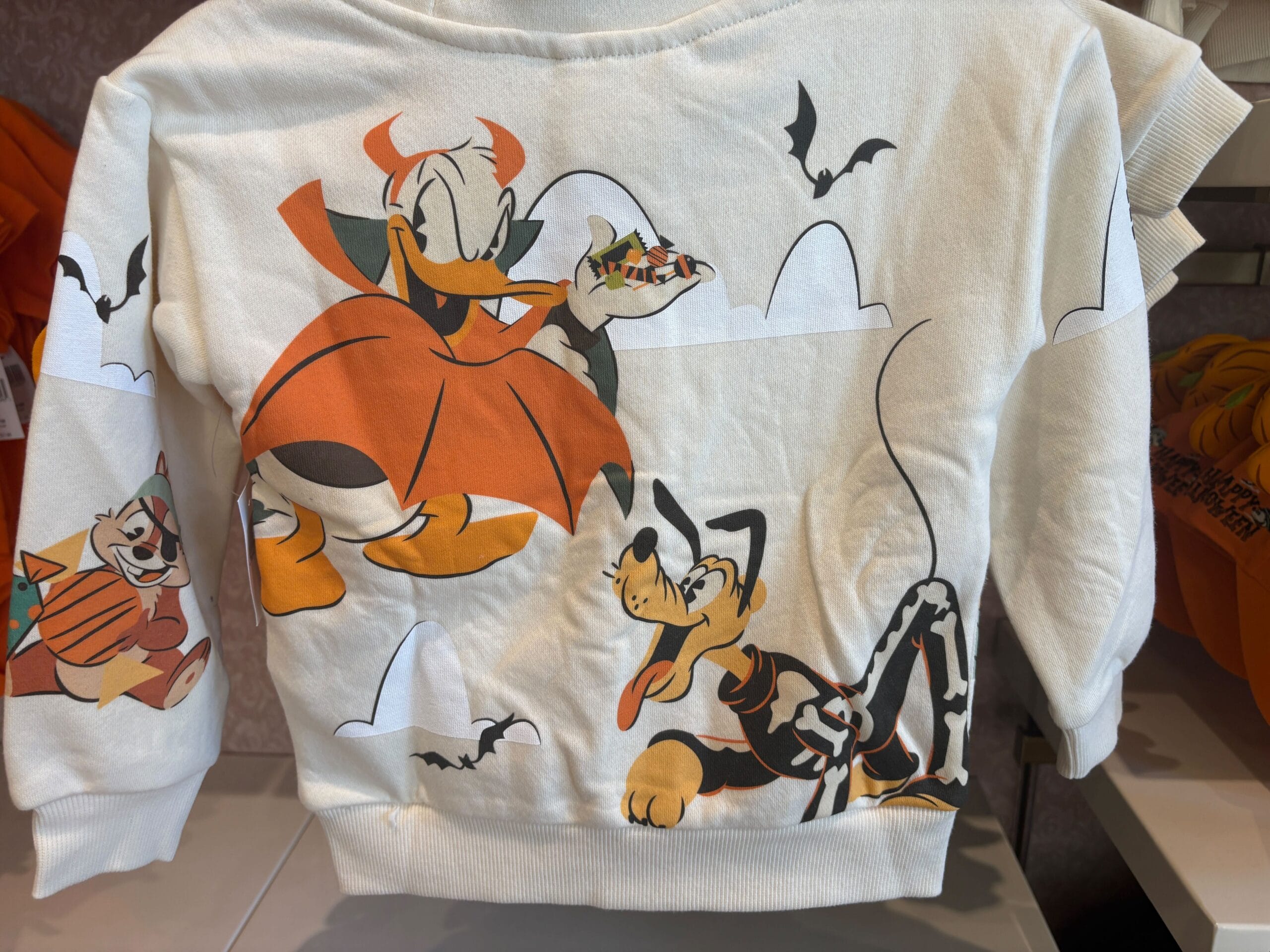 White sweatshirt with Walt Disney World Halloween characters, including Donald Duck as a devil and bats, festive Halloween merchandise.