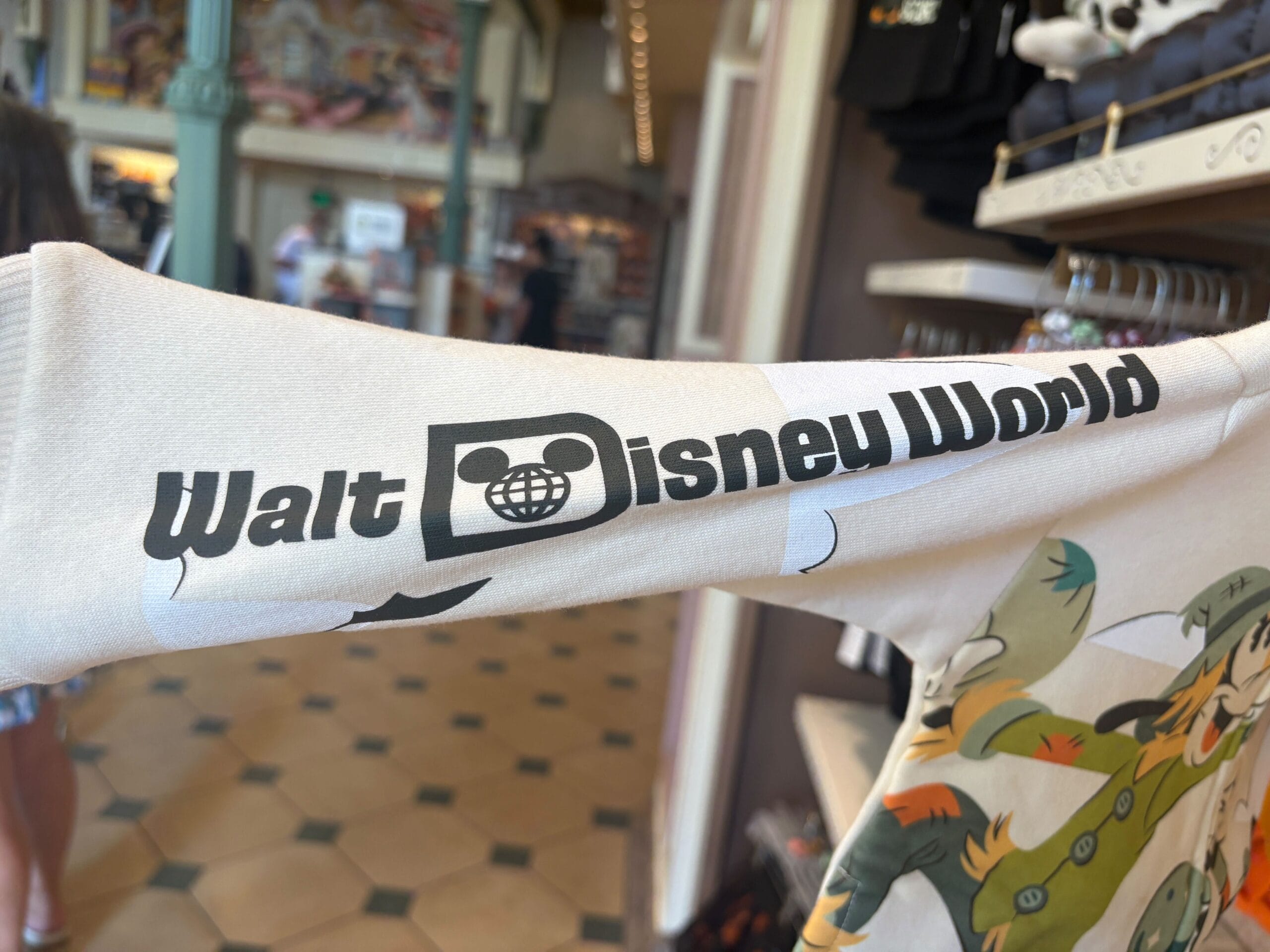 A shirt sleeve featuring the Walt Disney World logo in black text and a Mickey Mouse globe icon—perfect Halloween merchandise!