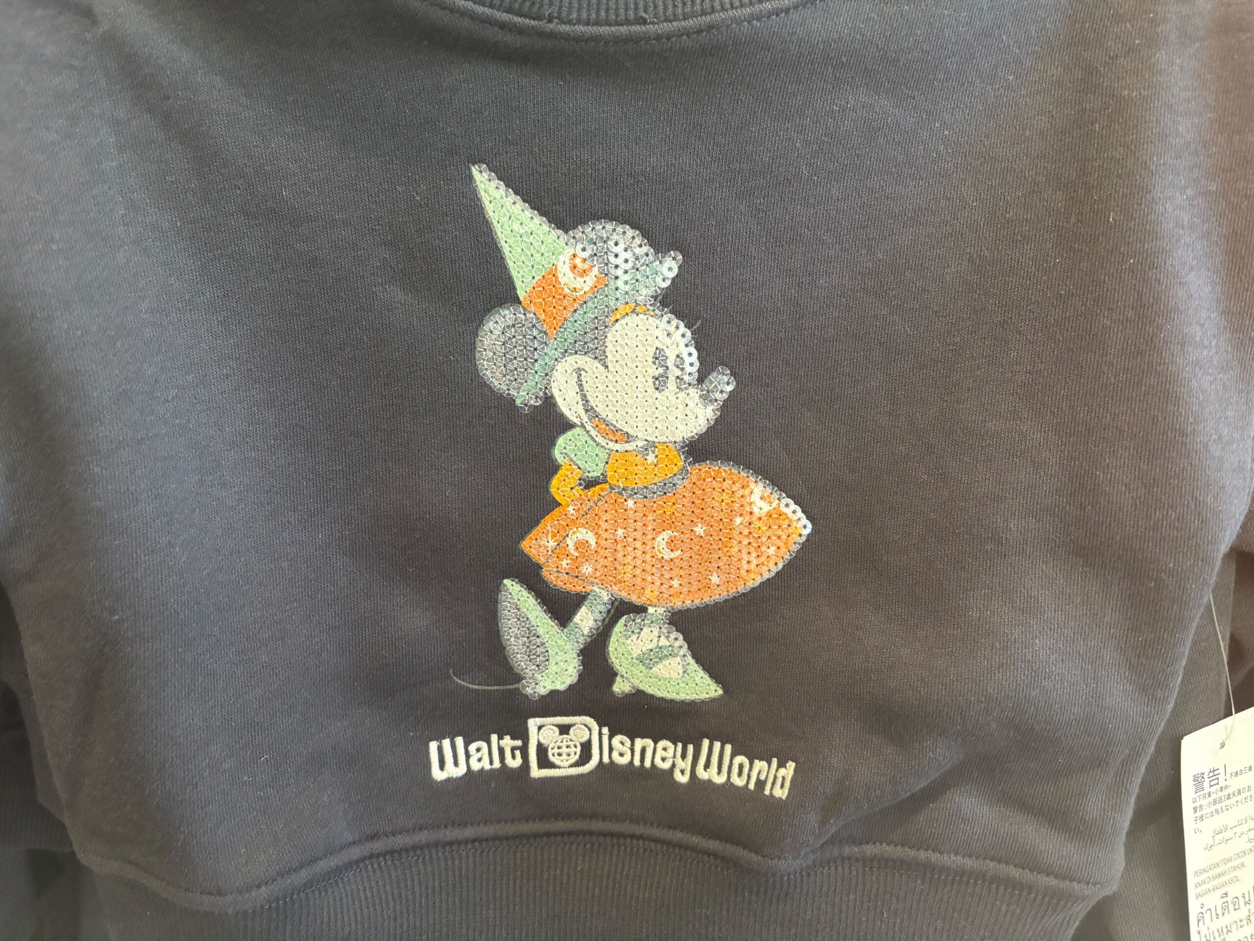 A sweatshirt featuring Minnie Mouse in a party hat and dress—fun Halloween merchandise from Walt Disney World.