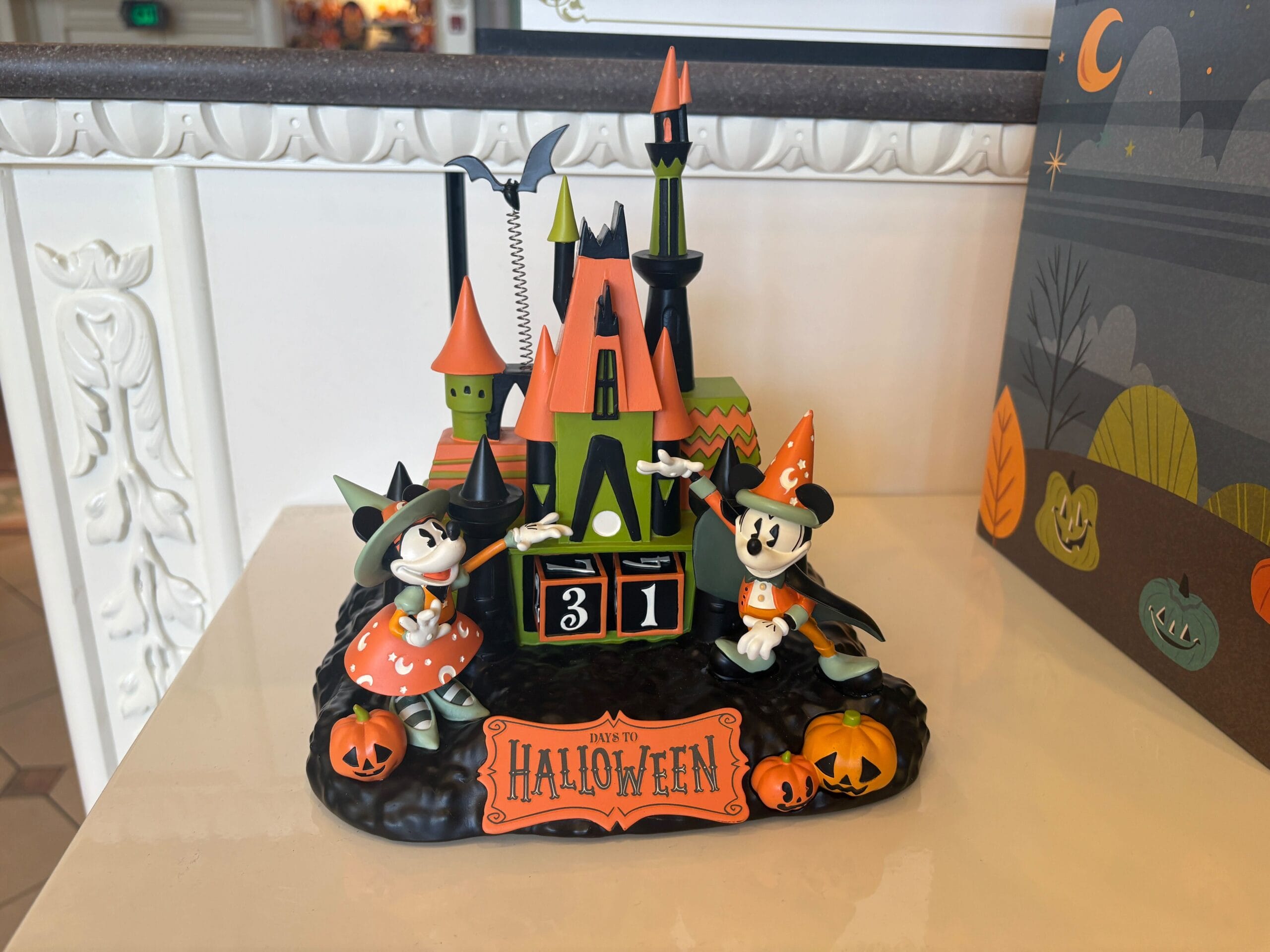 Mickey and Minnie in Halloween costumes stand by a Walt Disney World countdown calendar—31 days to Halloween.