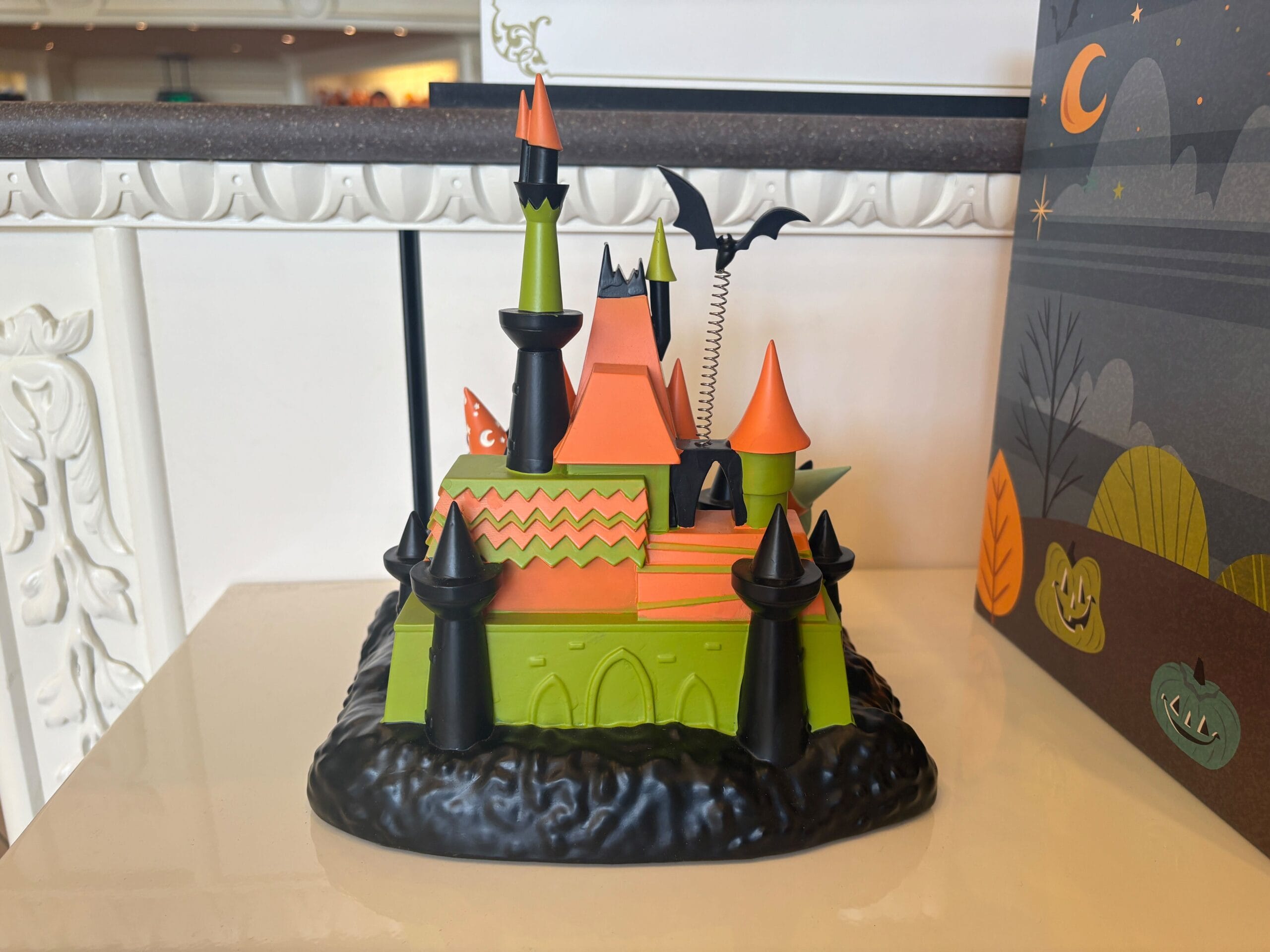 A colorful, cartoonish haunted castle inspired by Walt Disney World with orange and green walls and a bat on top.