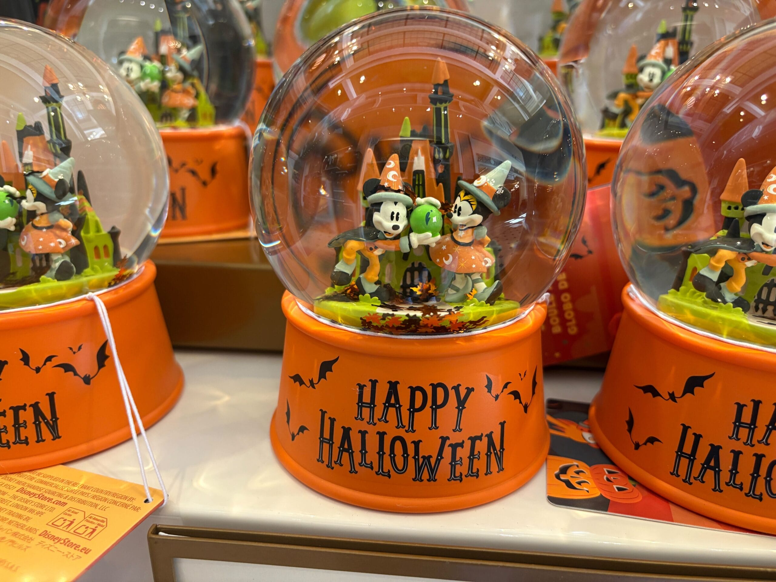Halloween snow globe with cartoon mice in costumes, orange base—festive Walt Disney World Halloween merchandise.
