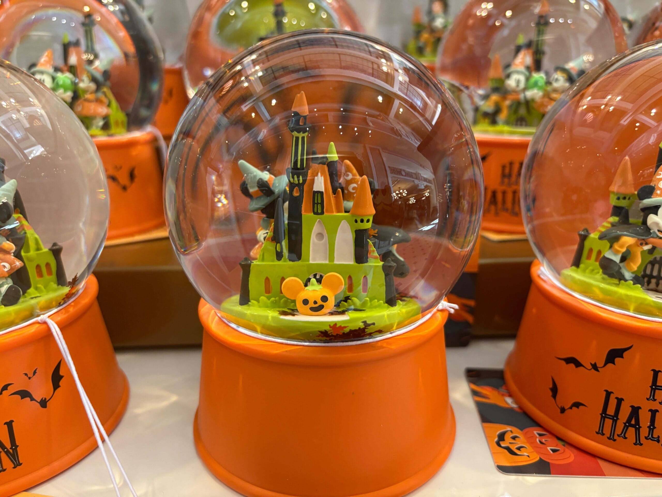 A Halloween snow globe featuring a spooky castle and pumpkins, inspired by Walt Disney World Halloween merchandise.