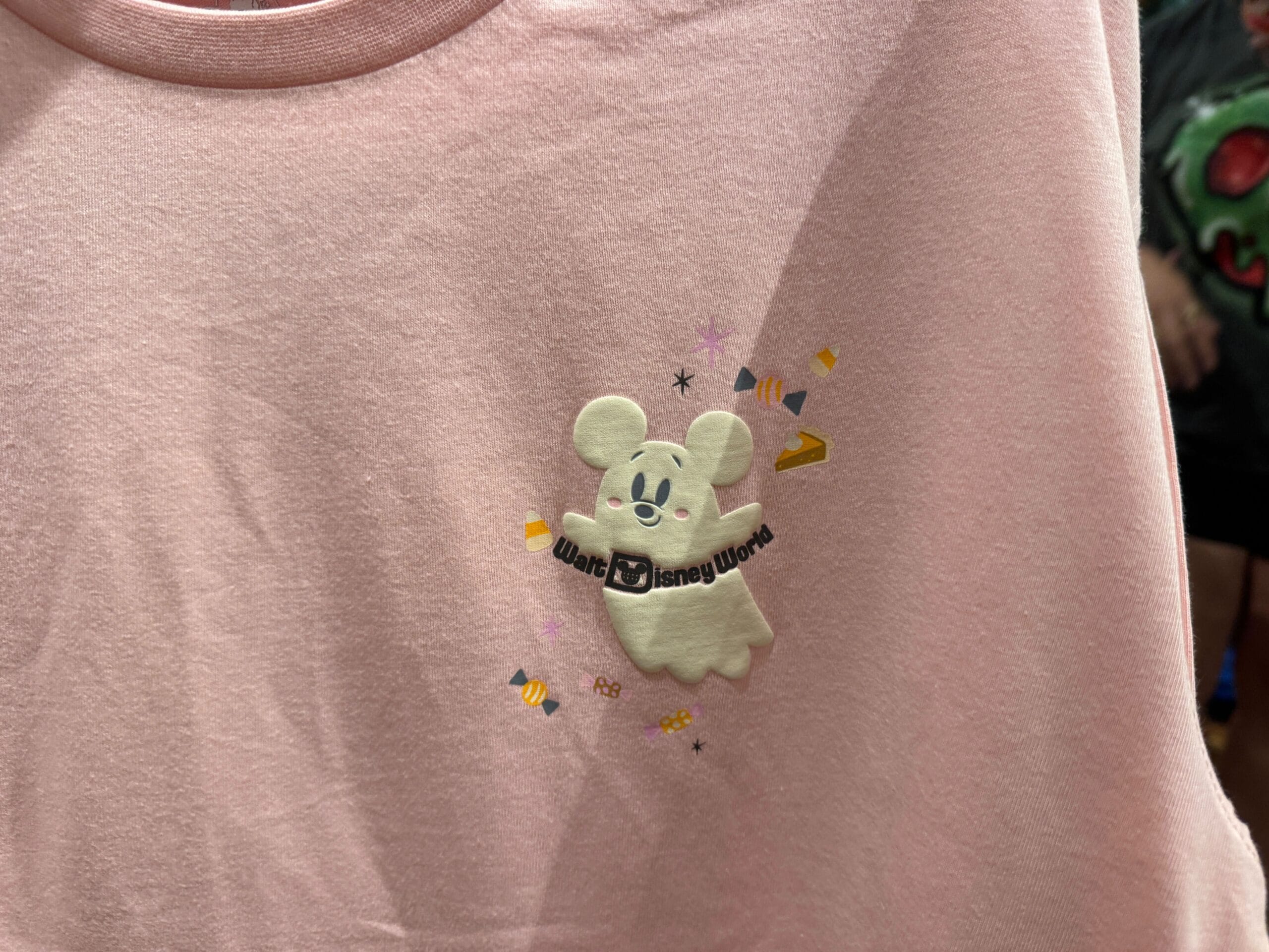 A pink shirt with a ghostly Mickey Mouse, "Walt Disney World" text, and festive Halloween merchandise accents.