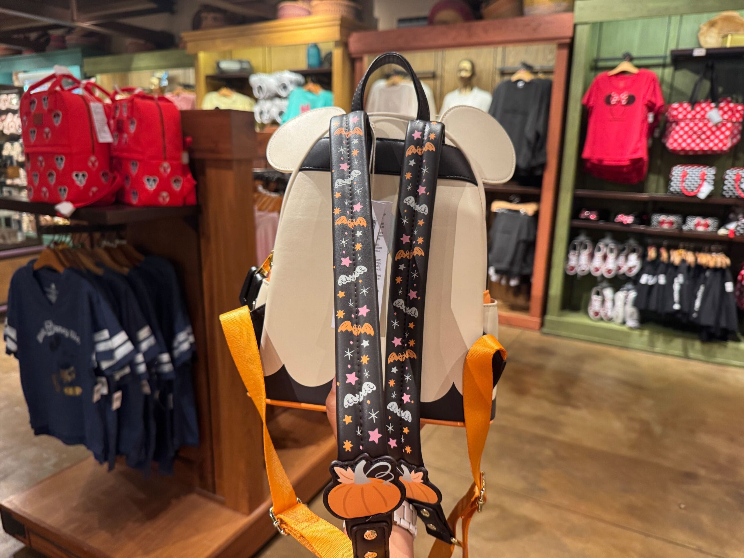 A Halloween-themed backpack with festive straps is displayed among Walt Disney World Halloween merchandise in the store.