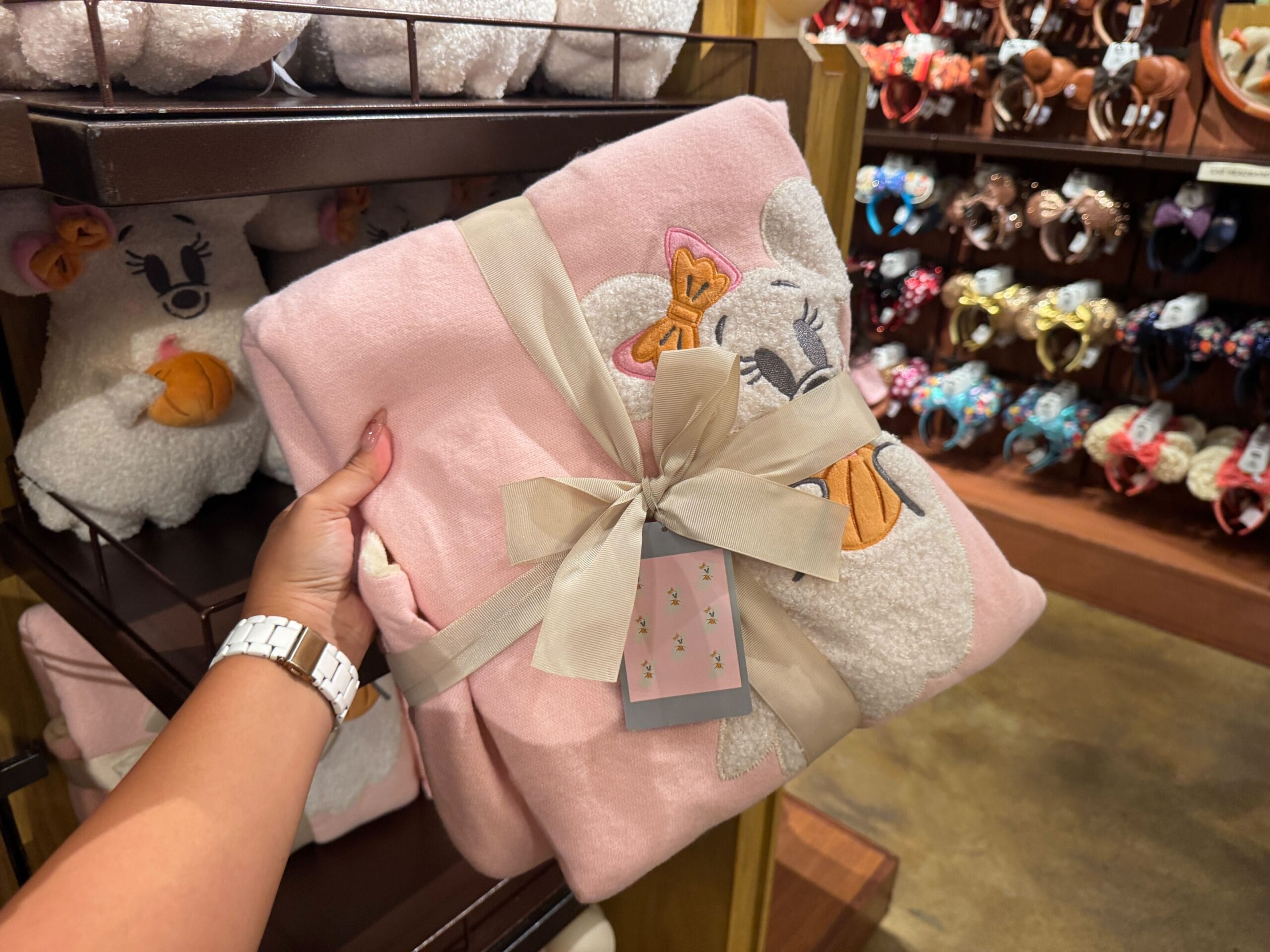 Person holding a pink Minnie Mouse blanket with a bow in a store featuring Halloween merchandise at Walt Disney World.