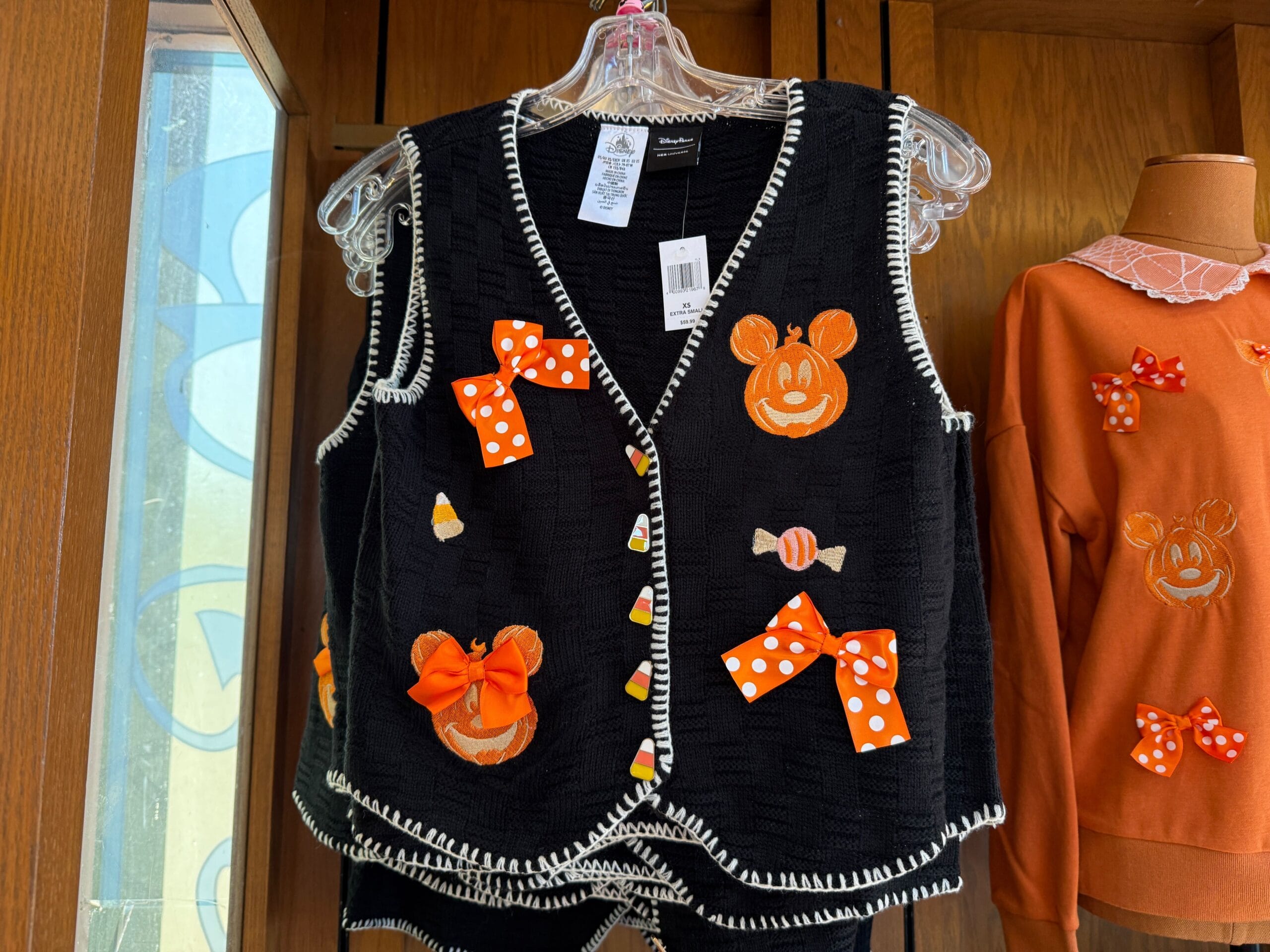 Black vest by Her Universe with orange Halloween Minnie Mouse faces, polka dot bows, and candy corn, seen at Disney World.