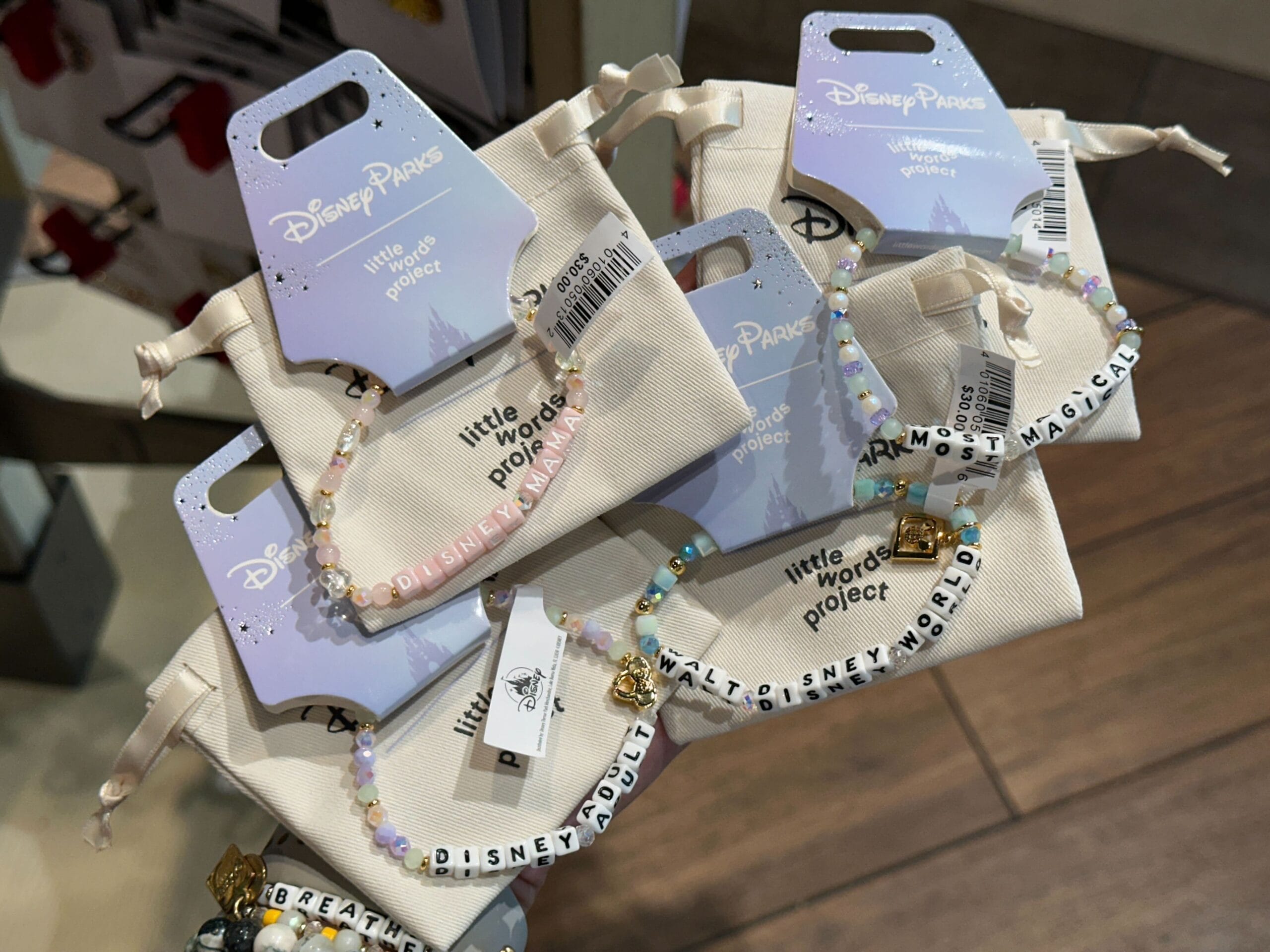 Beaded bracelets on display with Disney-themed words like "DISNEY ADULT" and "MOST MAGICAL," on retail packaging.