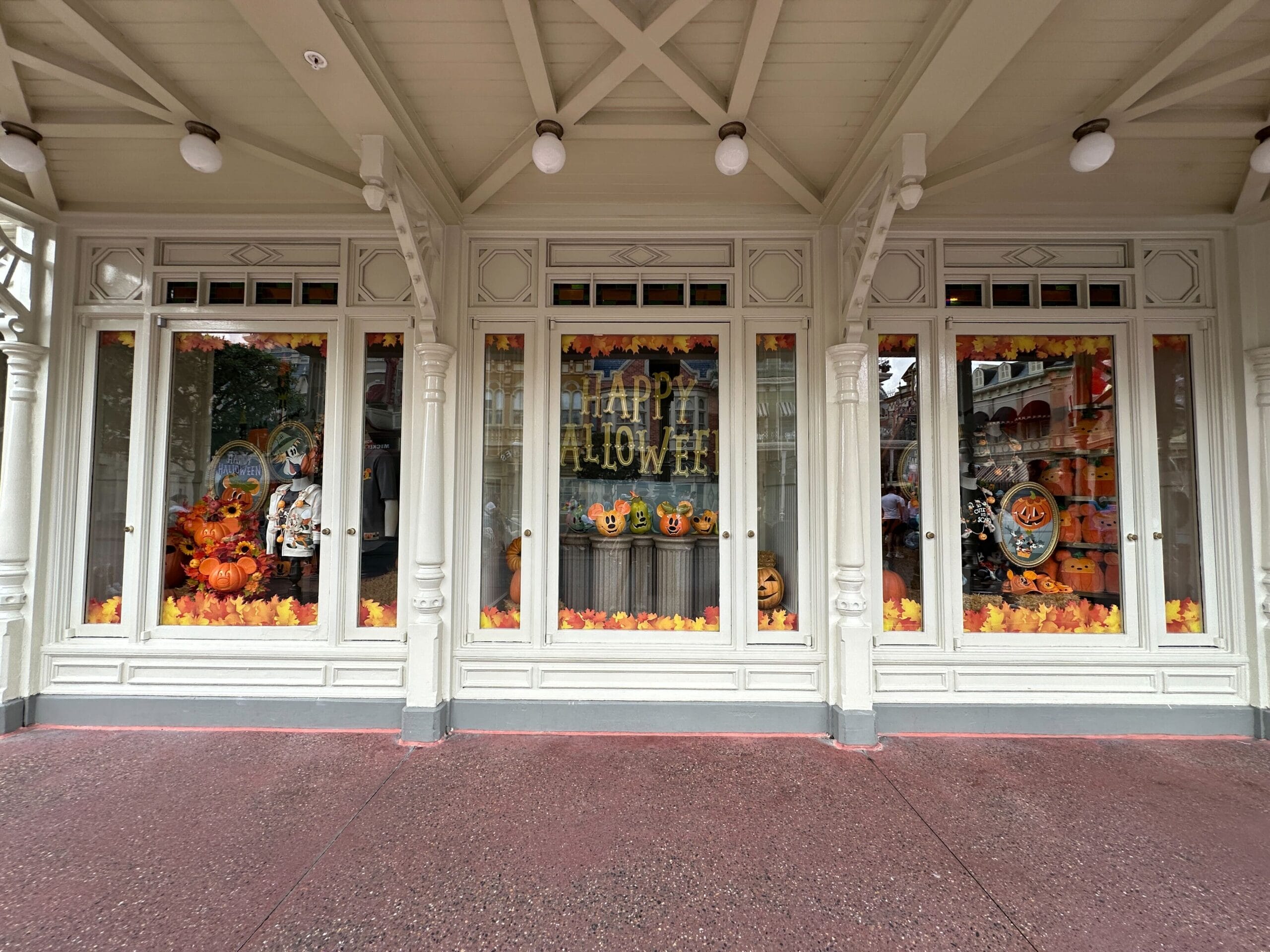 Storefront windows decorated with pumpkins, autumn leaves, and a "Happy Halloween" sign.