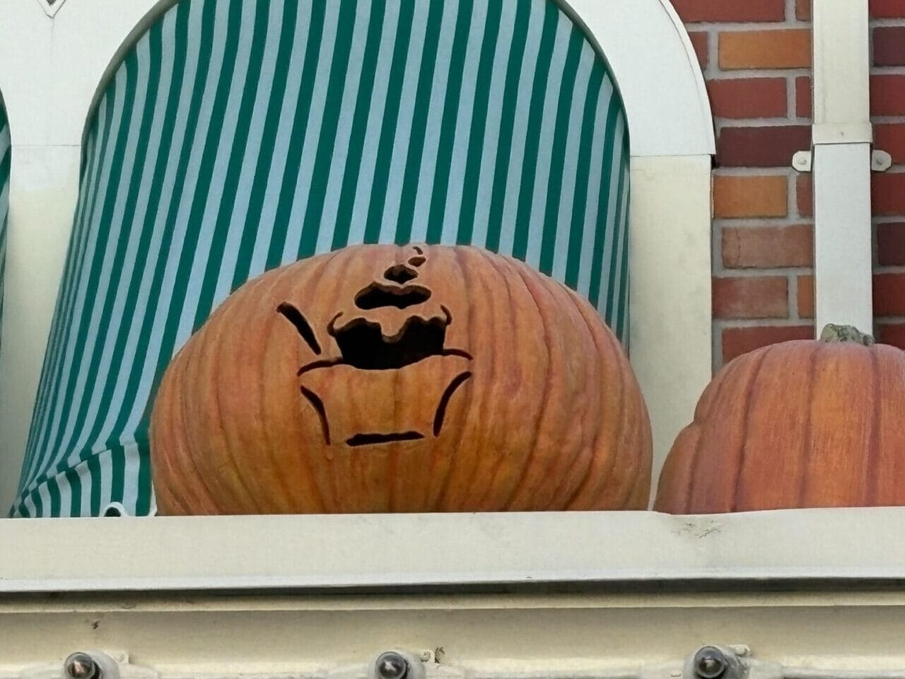 Two Jack-o'-Lanterns on a ledge; one features a teapot design with steam—unique Halloween decor.