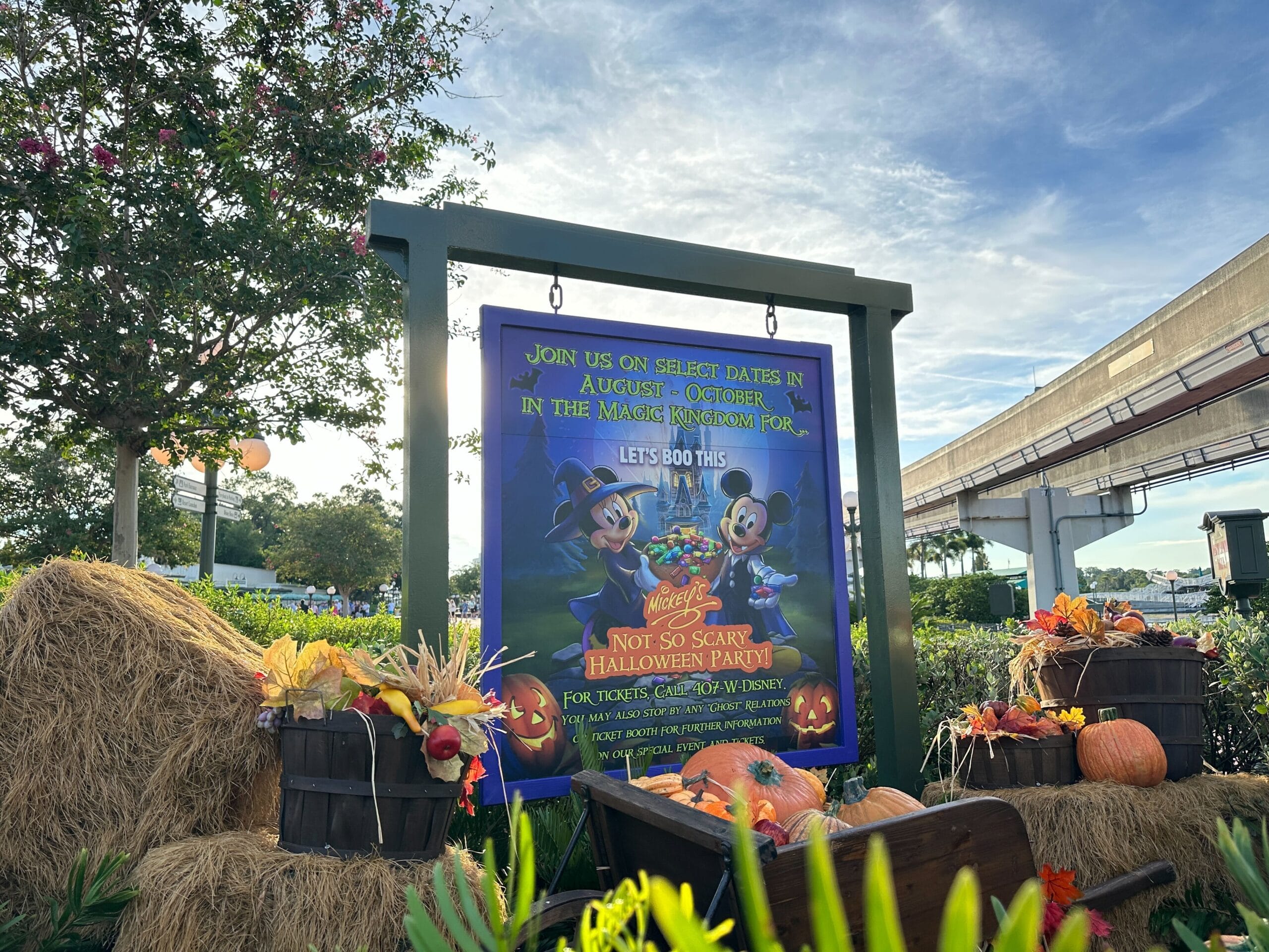 A Disney Mickey's Not So Scary Halloween party sign with Mickey and Minnie, surrounded by pumpkins, hay bales, and autumn decorations.