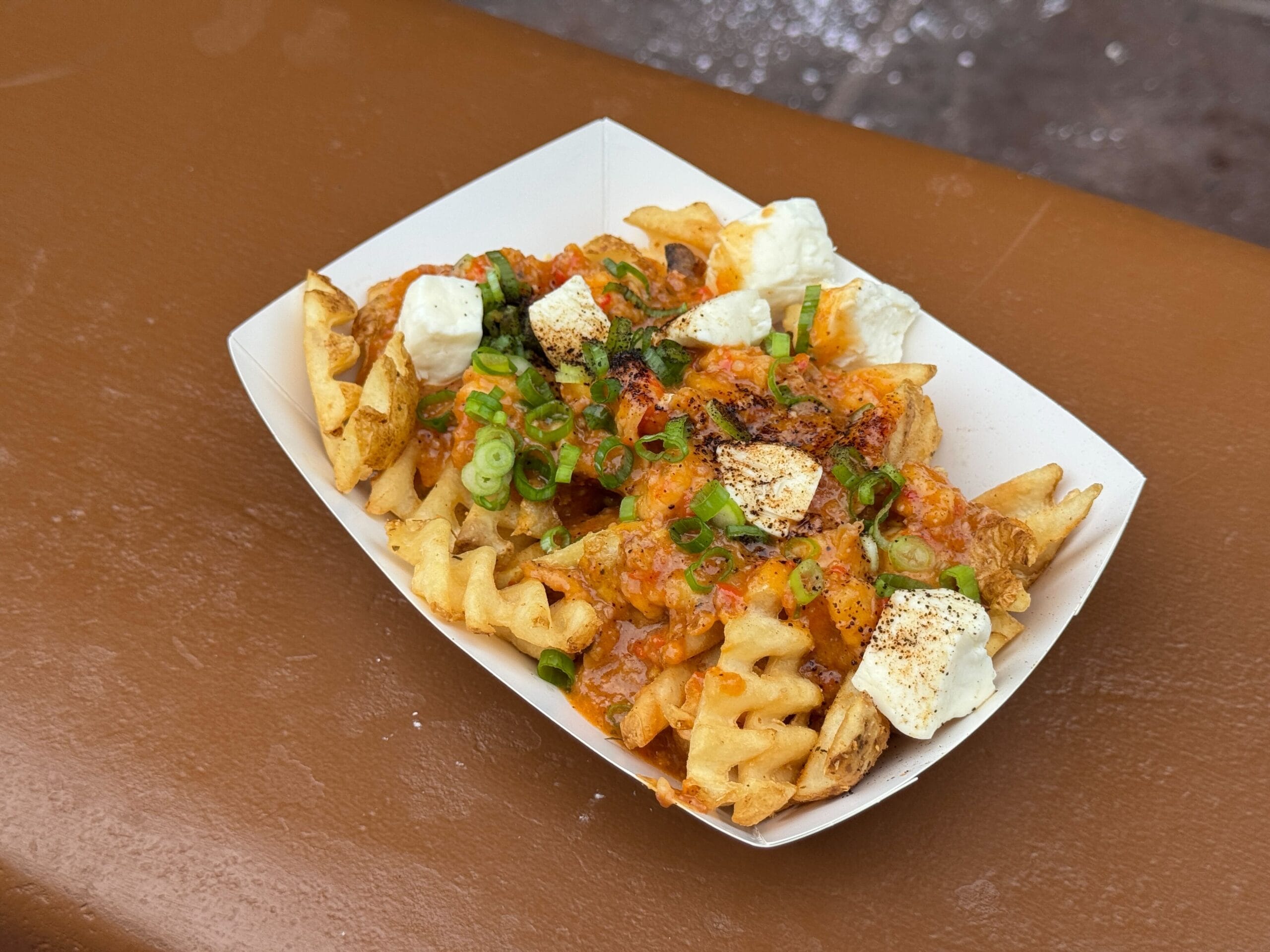 Waffle fries topped with cheese curds, green onions, and savory sauce—a hit at Mickey's Not So Scary Halloween Party.