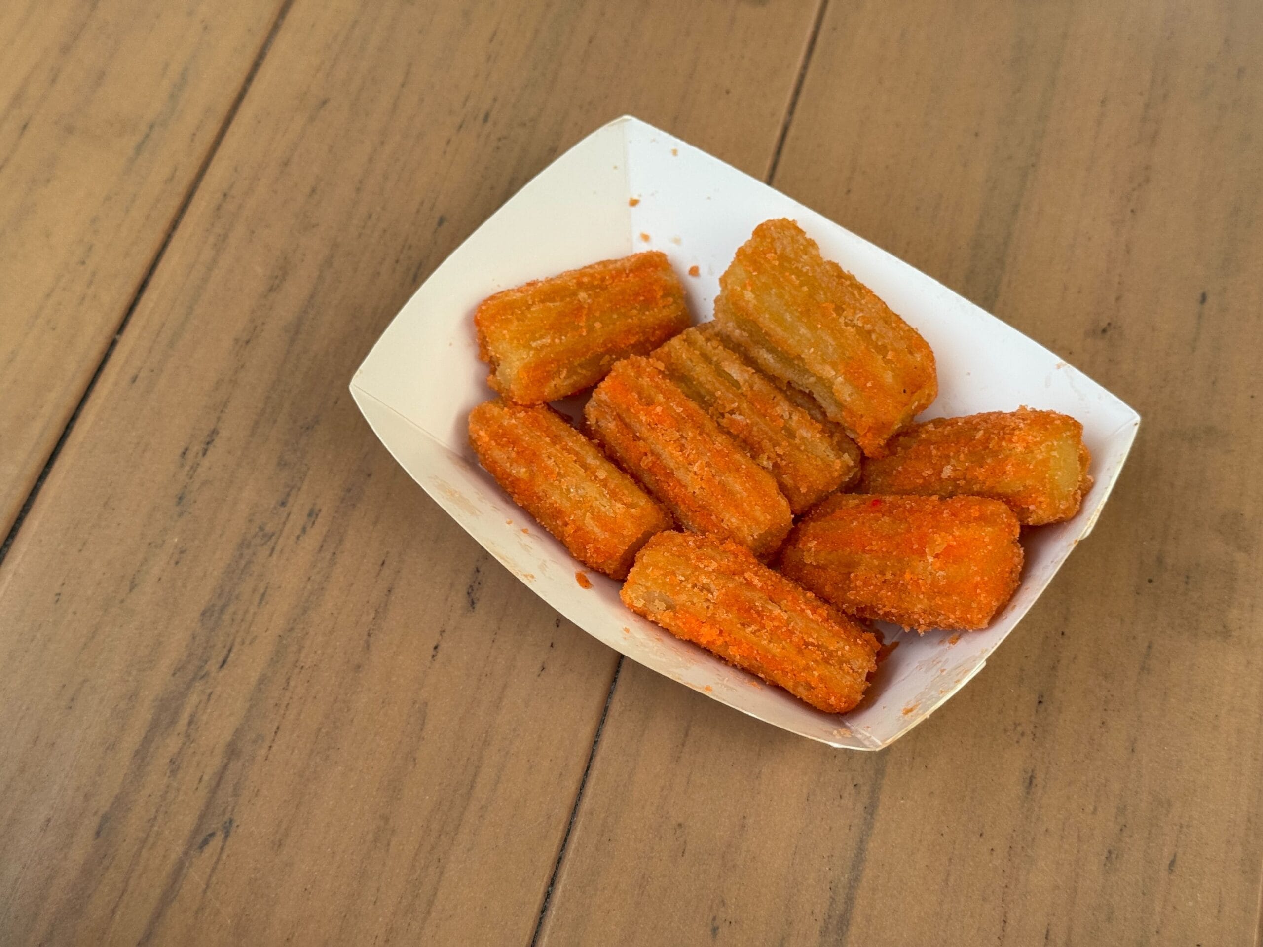 A small tray of mini churros coated in orange seasoning sits on a wooden table at Mickey's Not So Scary Halloween Party.
