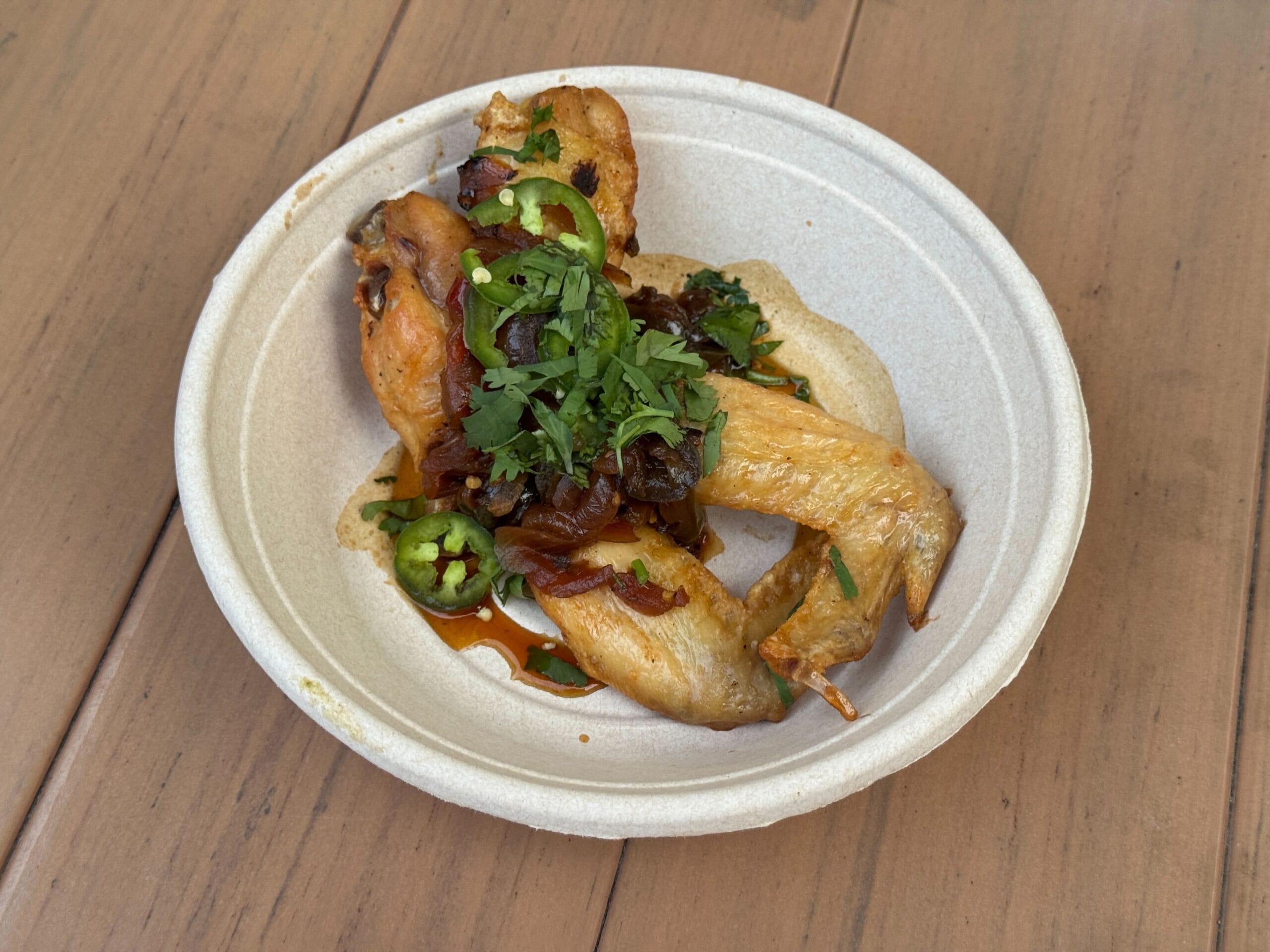 A paper bowl with chicken wings, jalapeños, and herbs—perfect for food reviews at Mickey's Not So Scary Halloween Party.