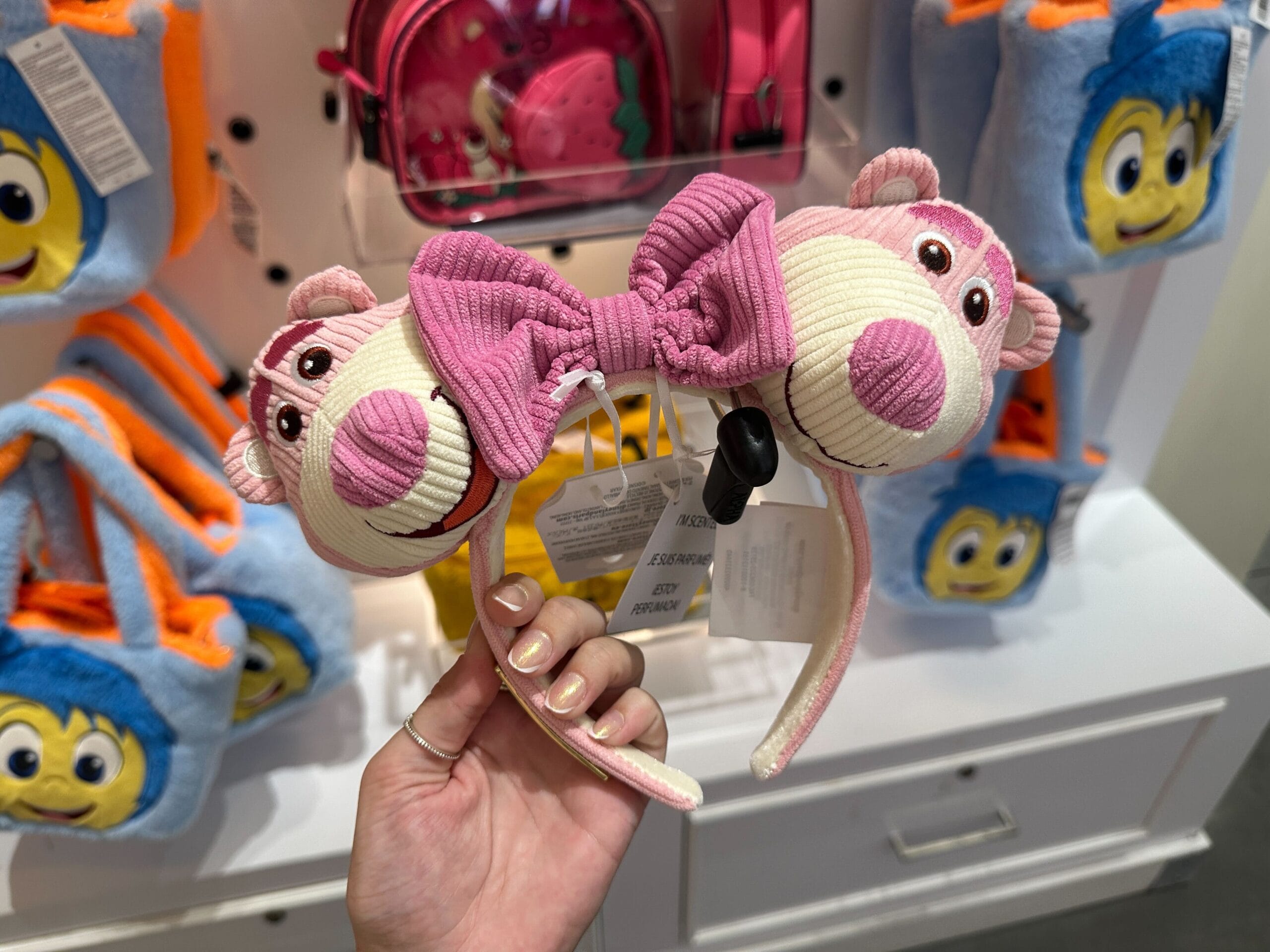 A hand holding a headband with a pink bow