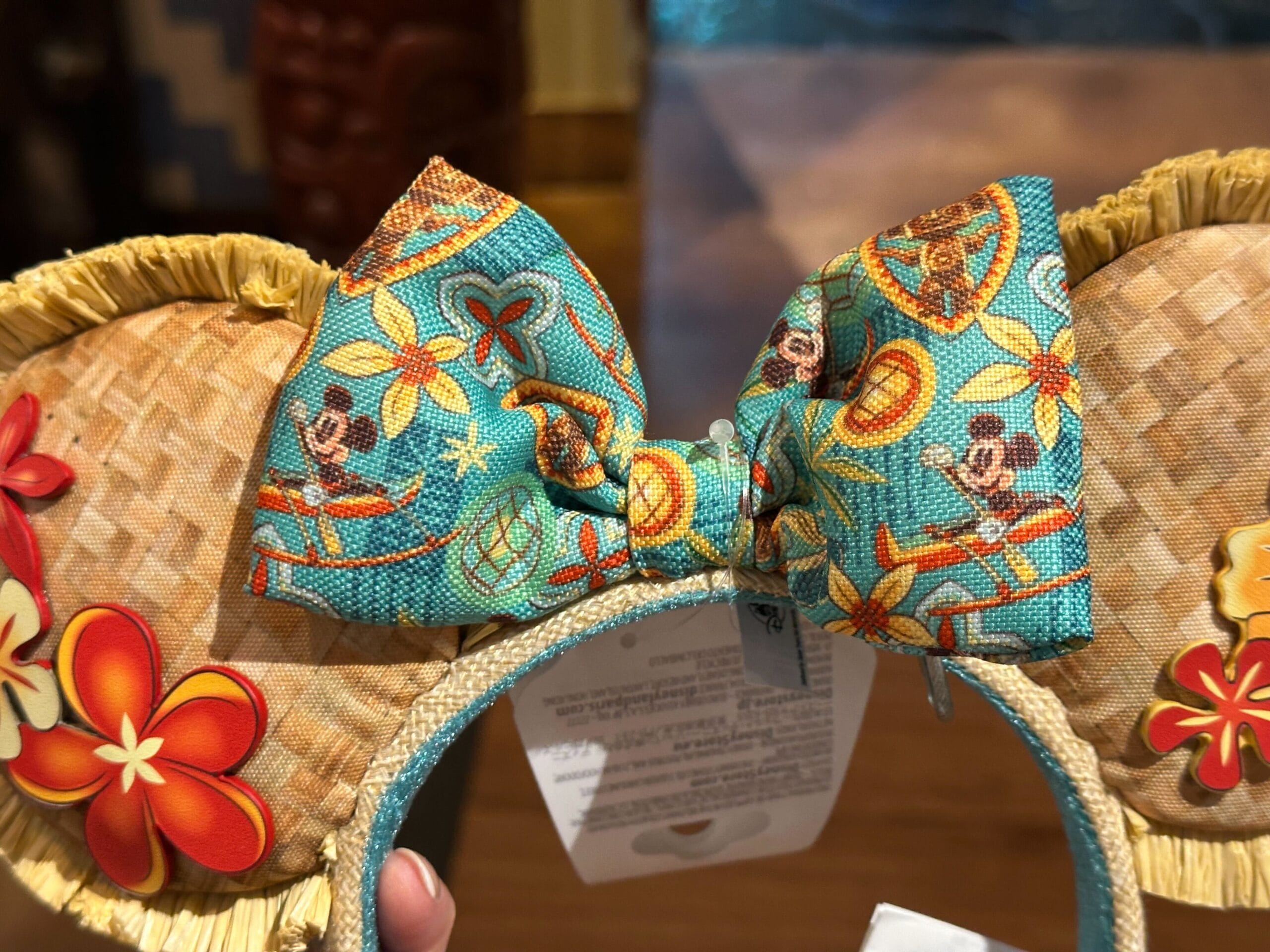 Close-up of Disney Minnie Mouse ears headband with tropical flowers and a teal bow featuring Mickey in Hawaiian attire.