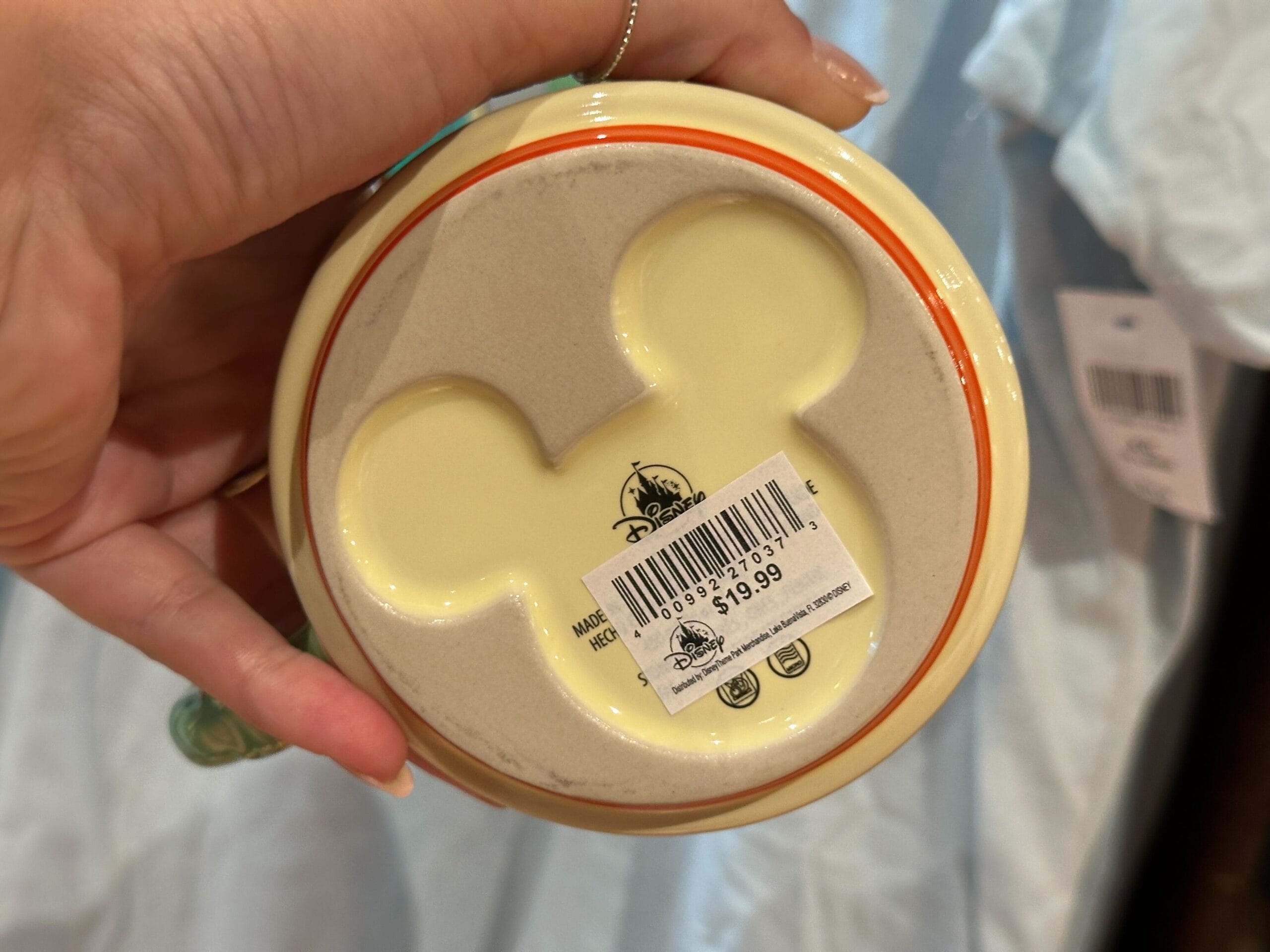 Hand holding a ceramic item with a Mickey Mouse head shape on the bottom and a $19.99 price sticker.