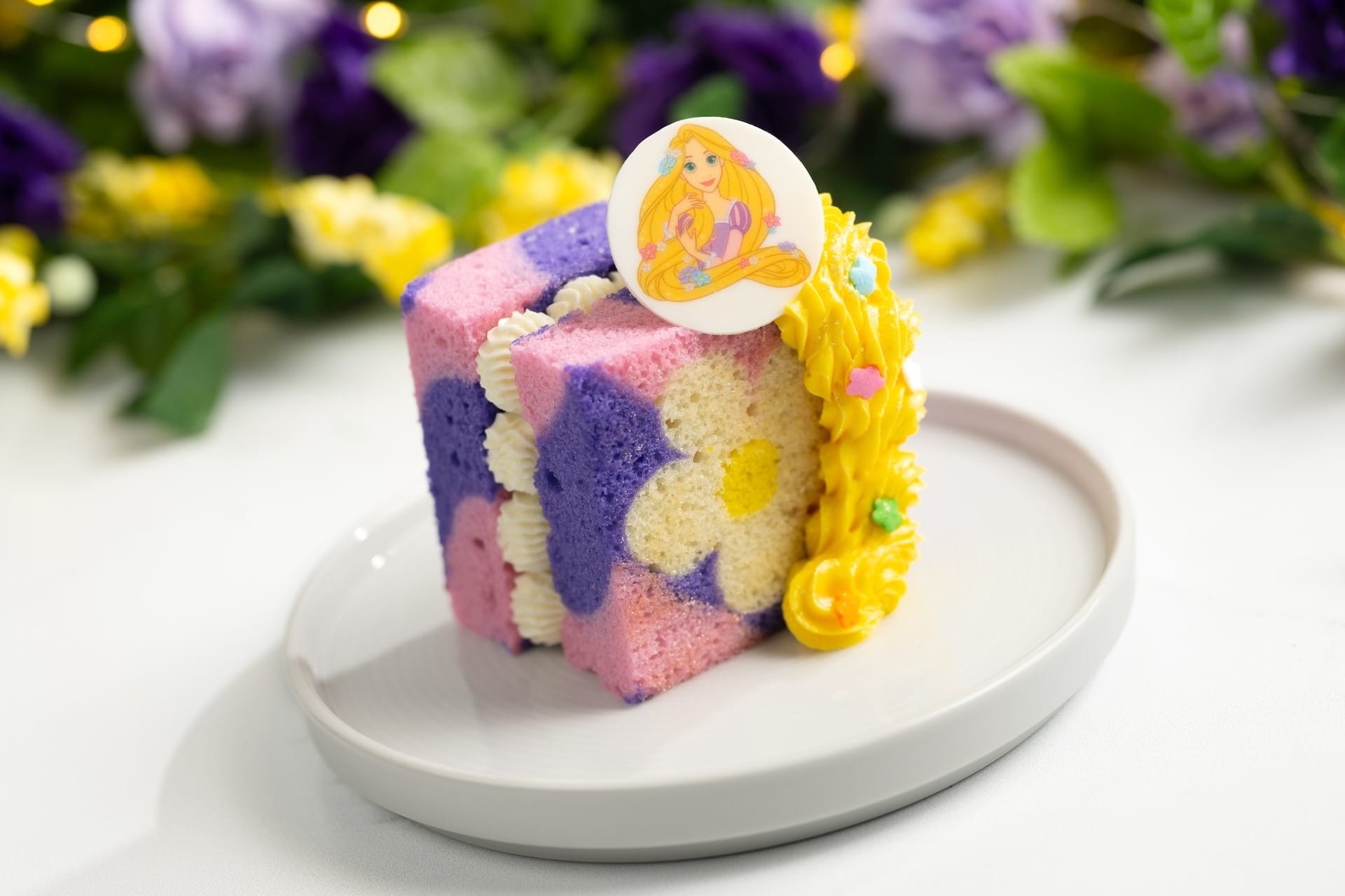 A pastel-colored cake with a Rapunzel topper, perfect for World Princess Week at Disneyland Paris.