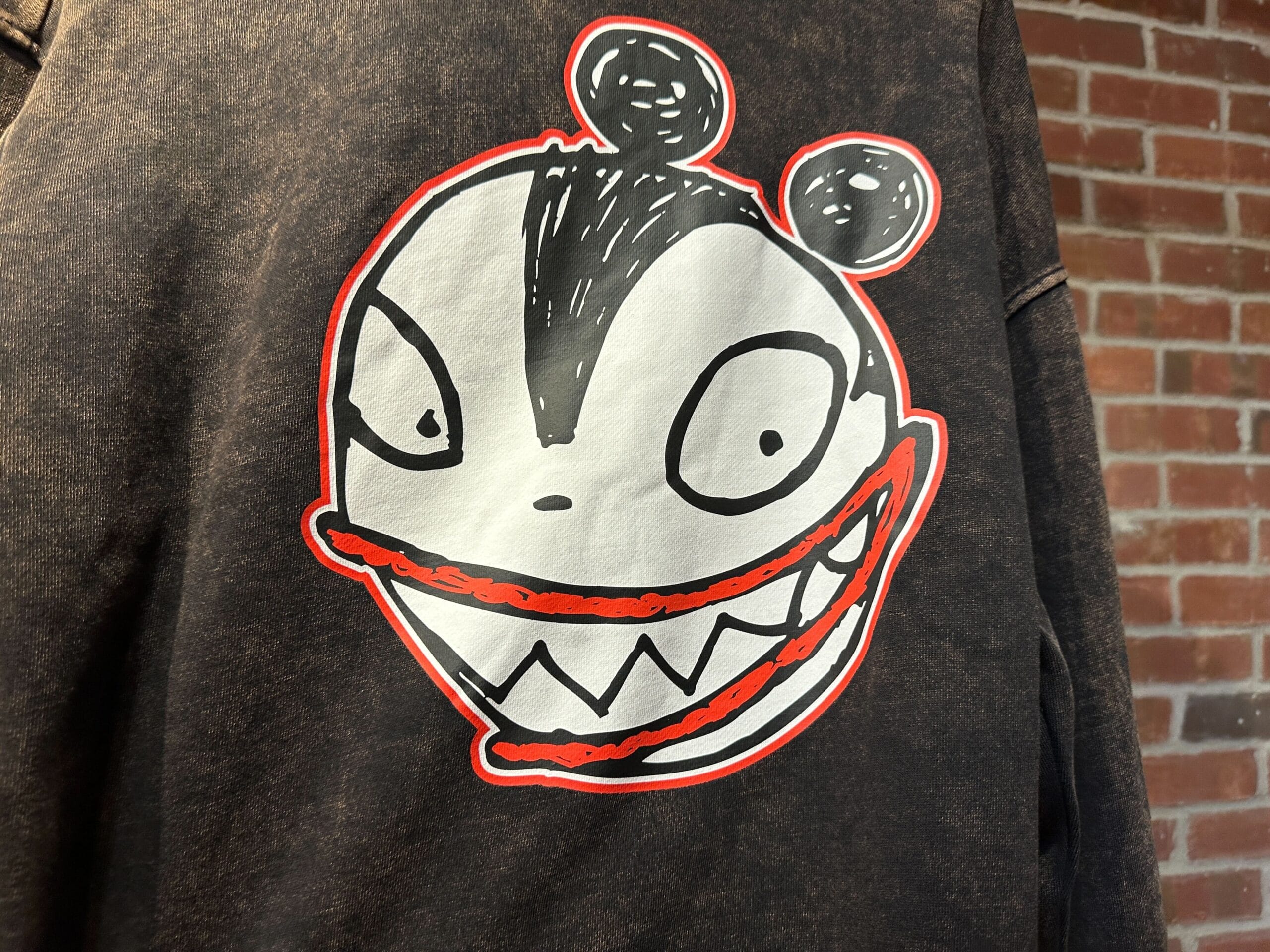 A black jacket with a large cartoon face graphic, inspired by 2025 Disney Halloween merch, on the back.
