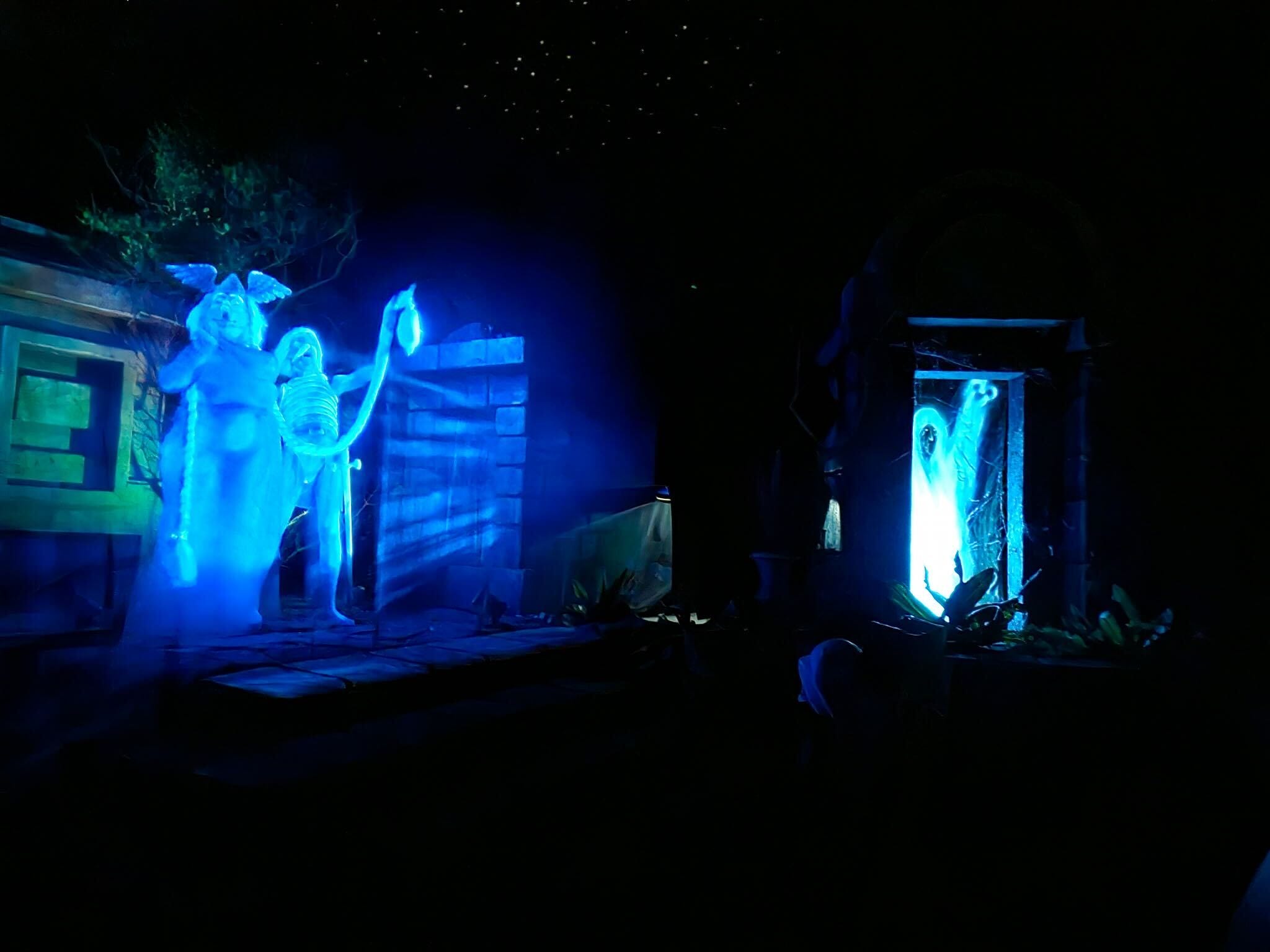 The graveyard scene in the Haunted Mansion in Walt Disney World, featuring a man and woman opera singer ghosts and the Hidden Mickey Shroud.