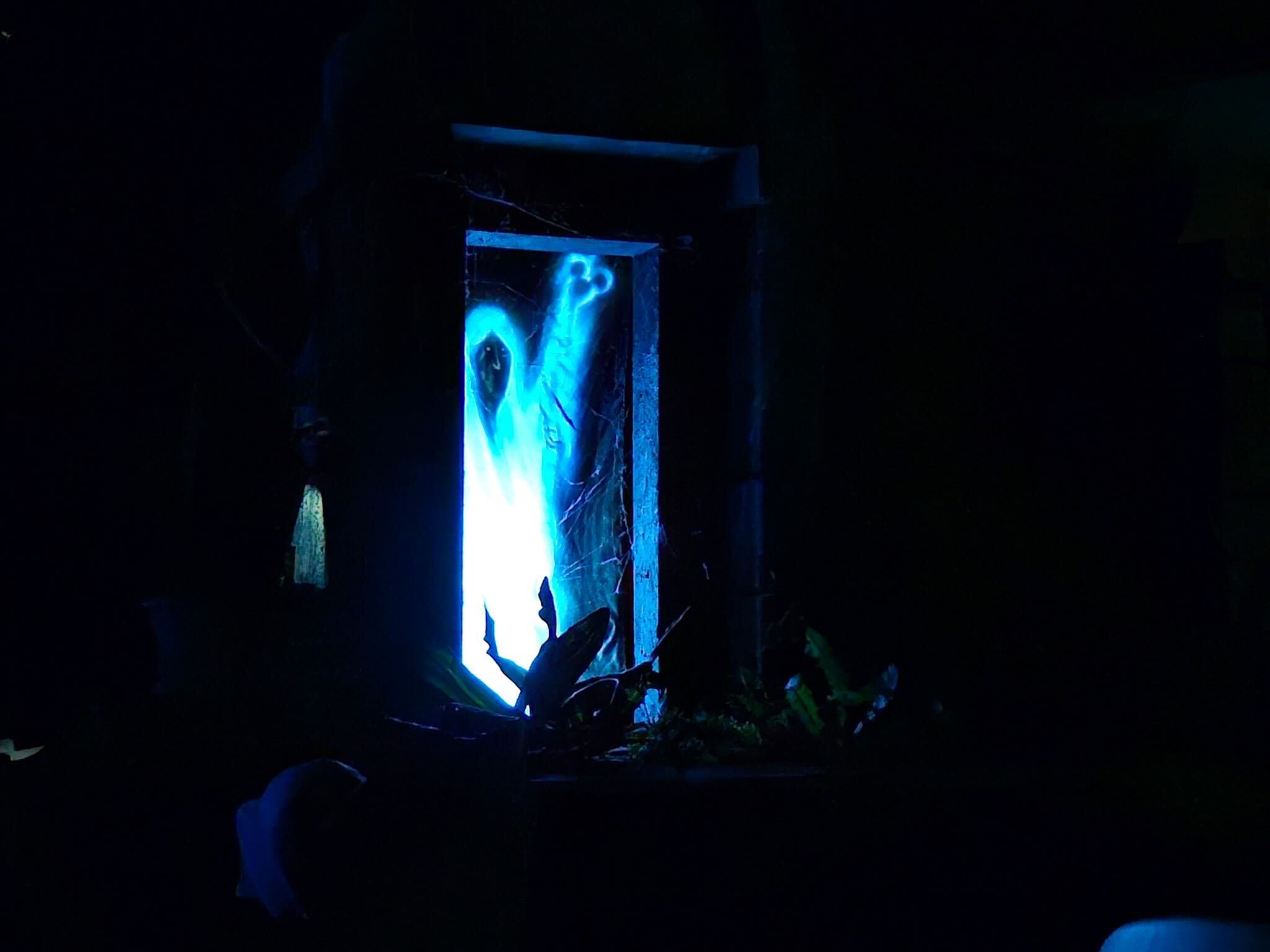 A glowing blue ghostly figure known as the Hidden Mickey Shroud appears in a crypt in the graveyard scene of the Haunted Mansion at Walt Disney World's Magic Kingdom.