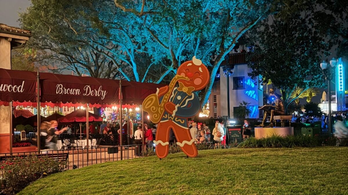 A statue of a gingerbread man playing a saxophone stands on the grass outside The Hollywood Brown Derby restaurant in Disney's Hollywood Studios during Jollywood Nights.