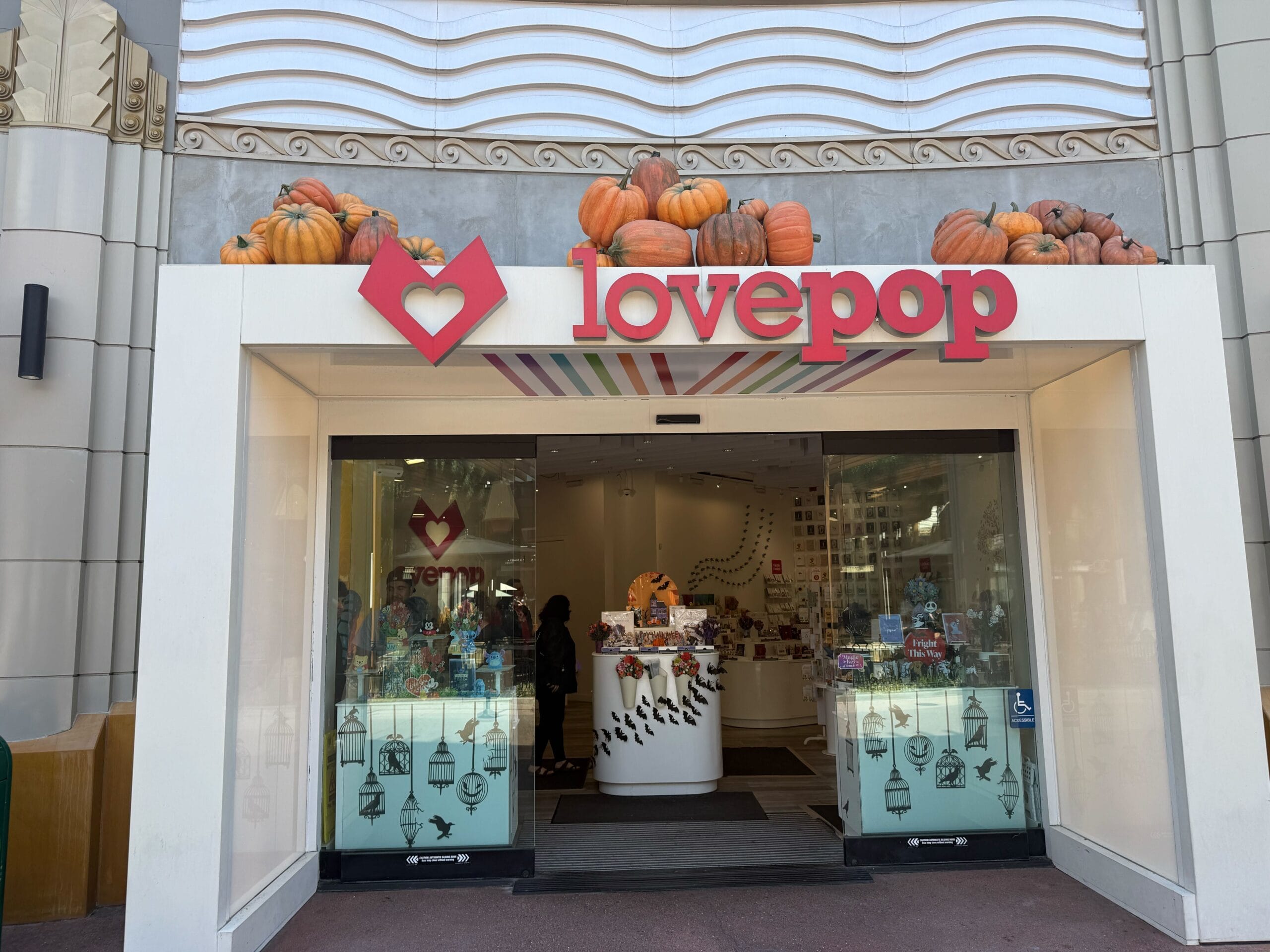 Lovepop store entrance decorated with pumpkins above the sign, showcasing colorful cards and gifts inside.