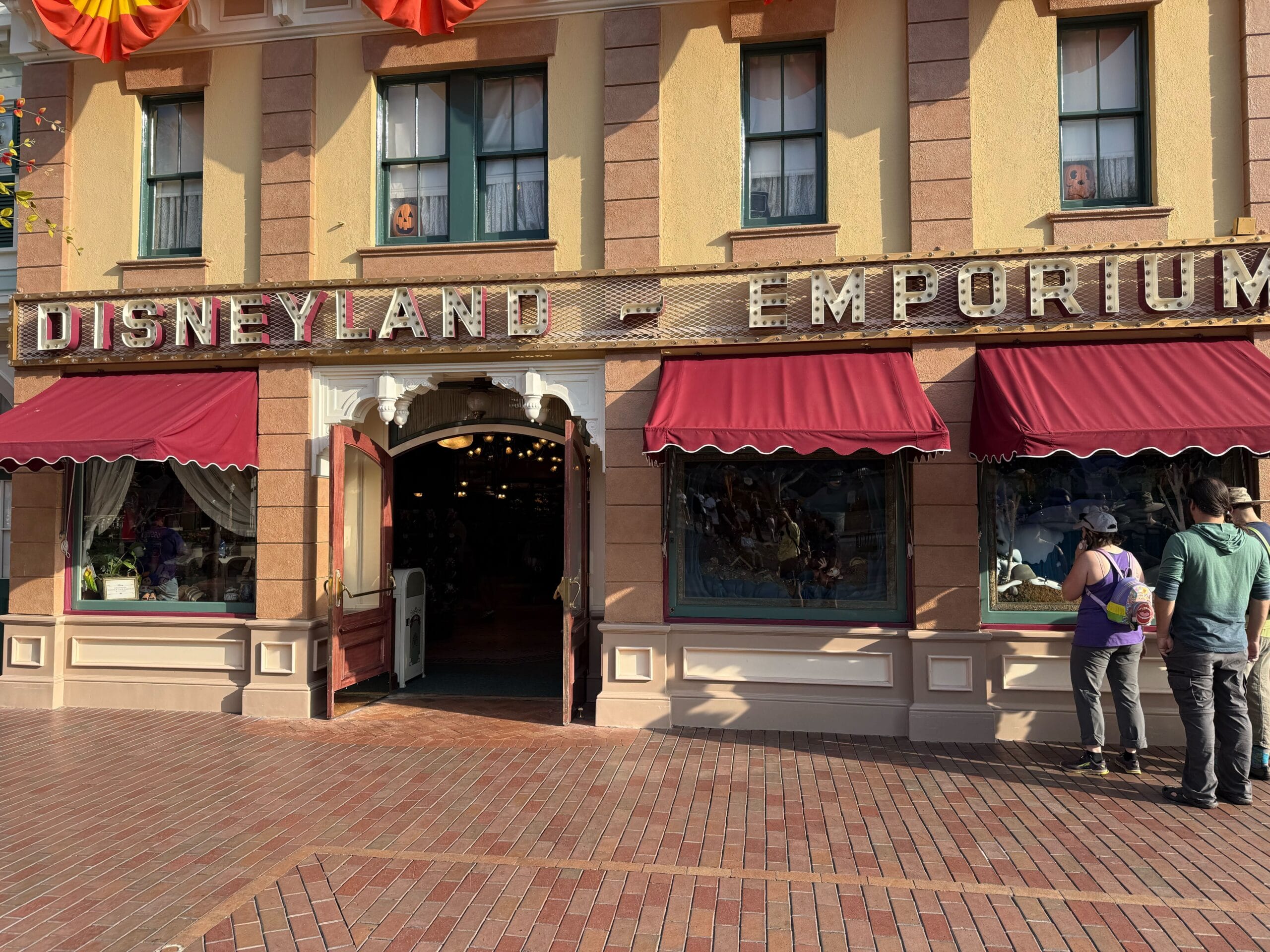The exterior of Disneyland Emporium with red awnings, open doors, and 70th anniversary decor outside.