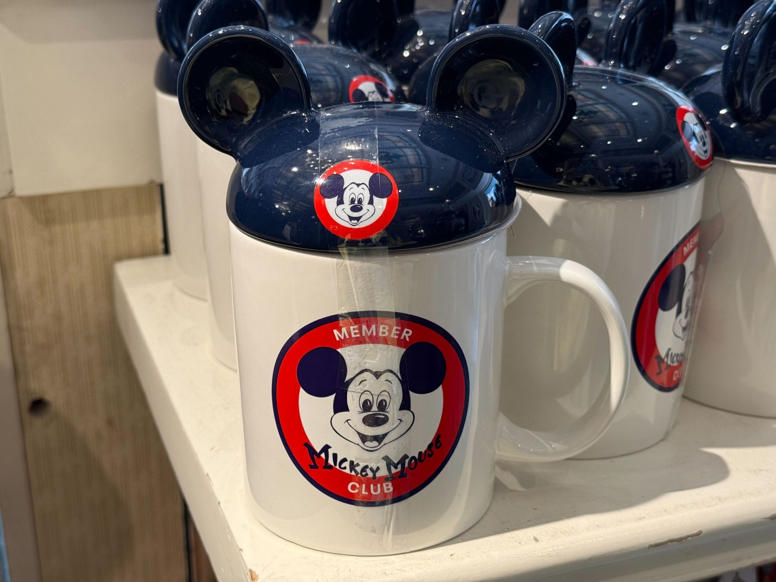 White mug with Mickey Mouse Club logo and Mickey ears lid, perfect Disneyland 70th anniversary merchandise.