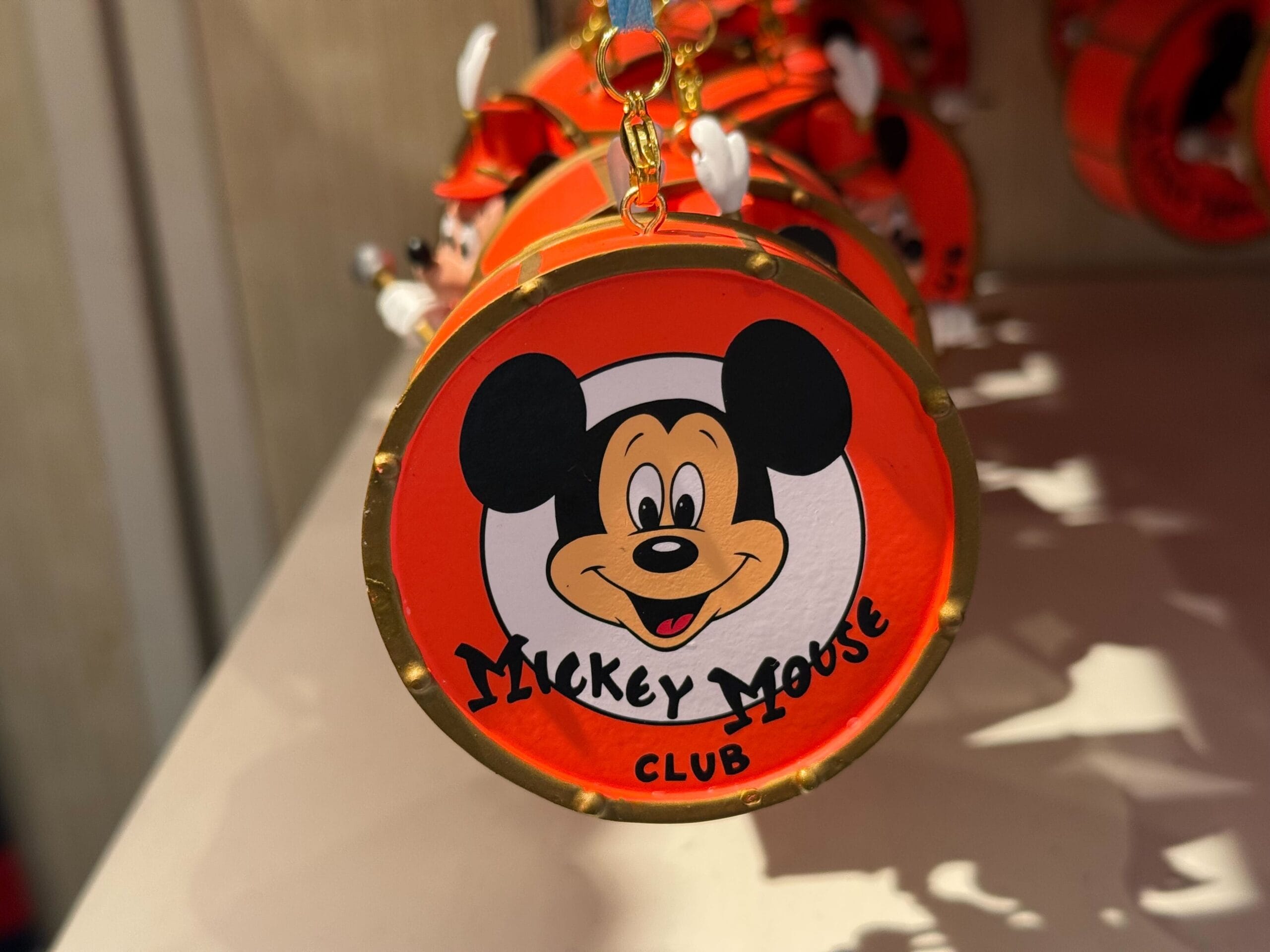 An ornament featuring the Mickey Mouse Club logo celebrates its 70th anniversary on a bright red background.