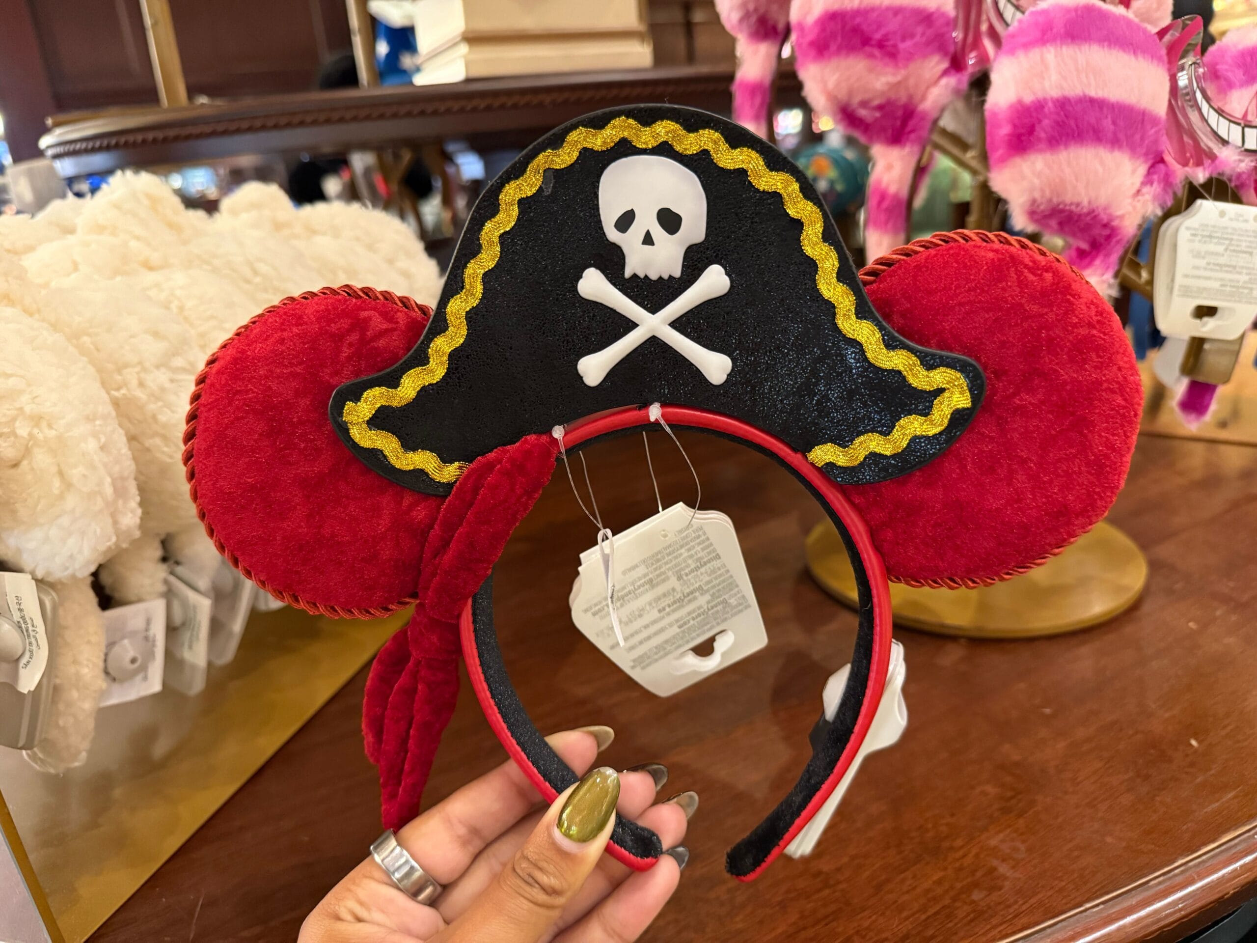 Red Minnie Mouse ears headband with a black pirate hat, inspired by Pirates of the Caribbean, displayed in a store.
