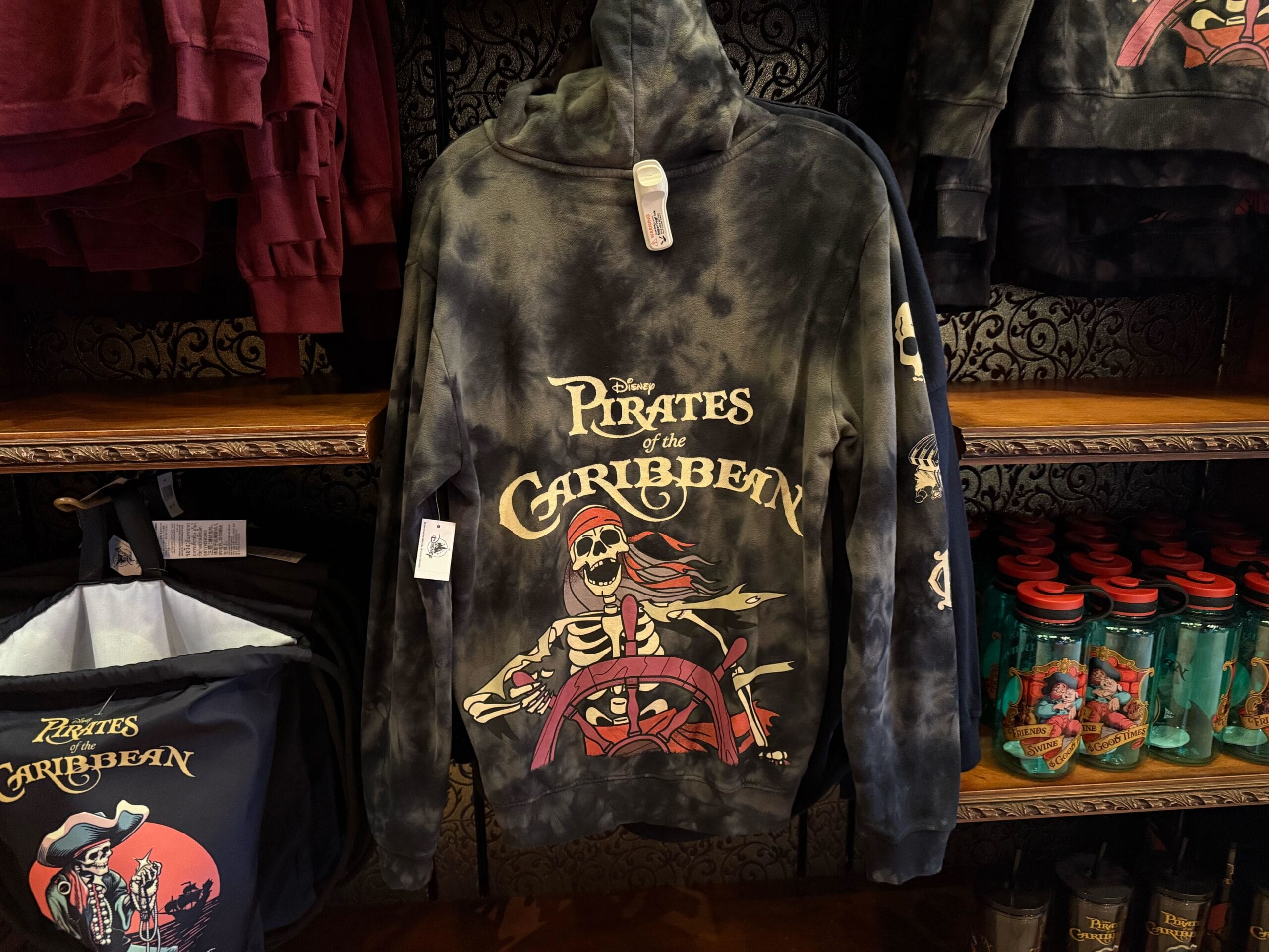 Black Pirates of the Caribbean hoodie with a skeleton pirate design, perfect Disneyland apparel, displayed on a store shelf.