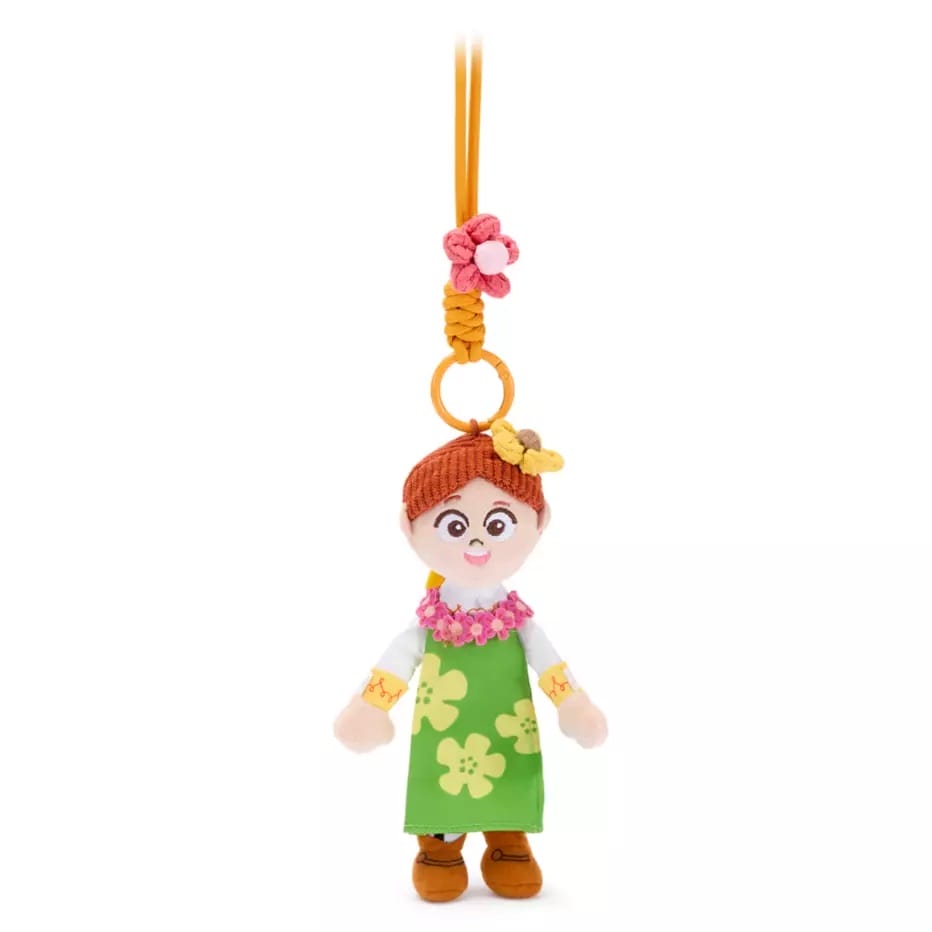 A keychain with a doll in a green dress and orange shoes, inspired by Toy Story bag charms, hanging by an orange loop.