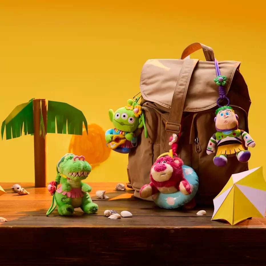A backpack with Toy Story Bag Charms and a beach umbrella on a wooden table, inspired by the Disney Store China.