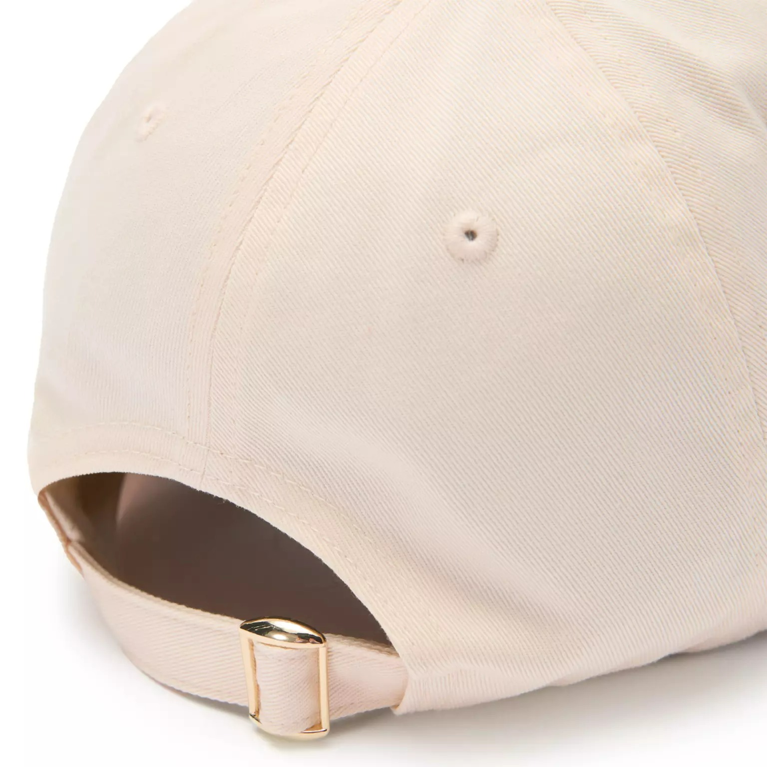 Close-up of the back of a beige baseball cap from the Disney Store with an adjustable strap and gold buckle.