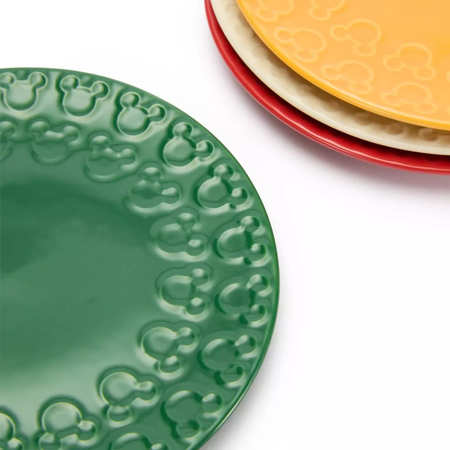 Three plates in green, yellow, and red with embossed Mickey edges, part of 2025 Disney Christmas merchandise.